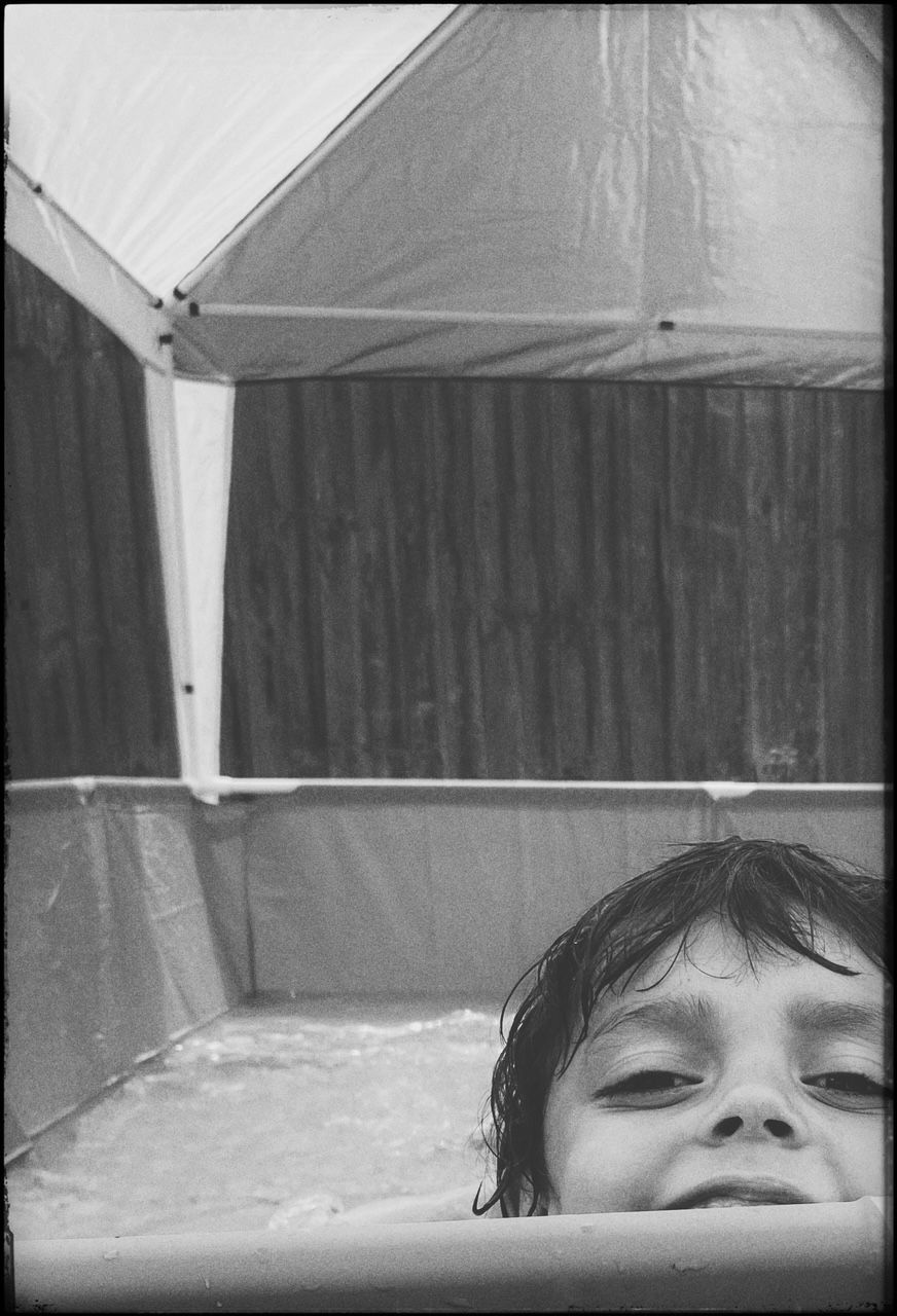 Black and white sequential photo series showing someone emerging from under a white sheet or blanket.