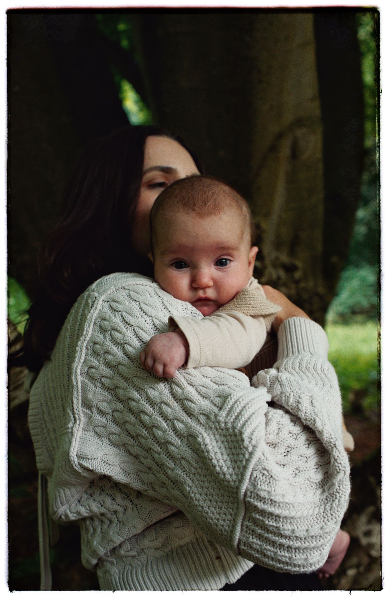 Gentle embrace captured against forest backdrop in warm natural lighting.