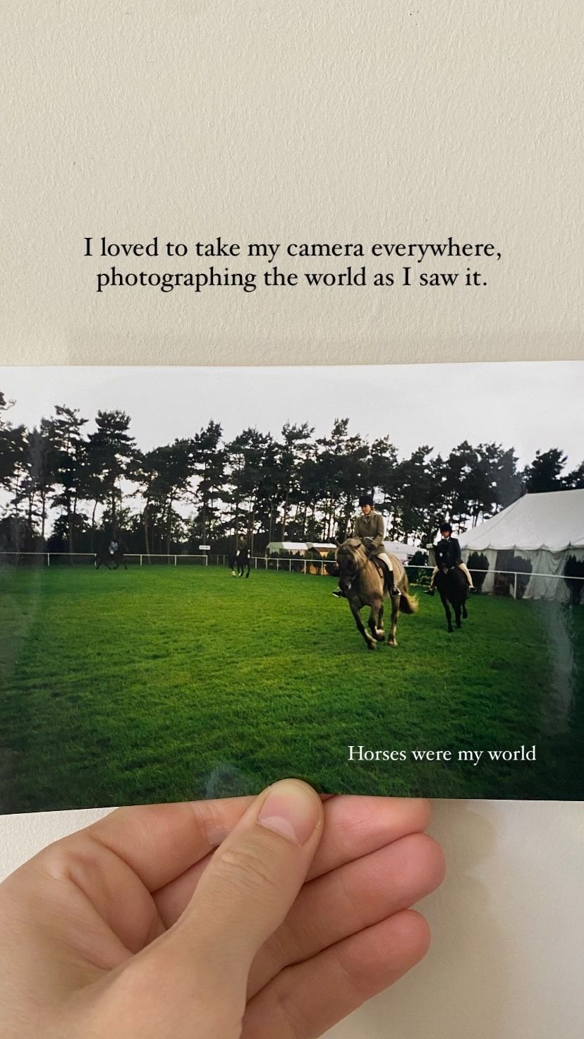 Someone holds vintage photographs showing horses running on a grassy field with trees in the background.