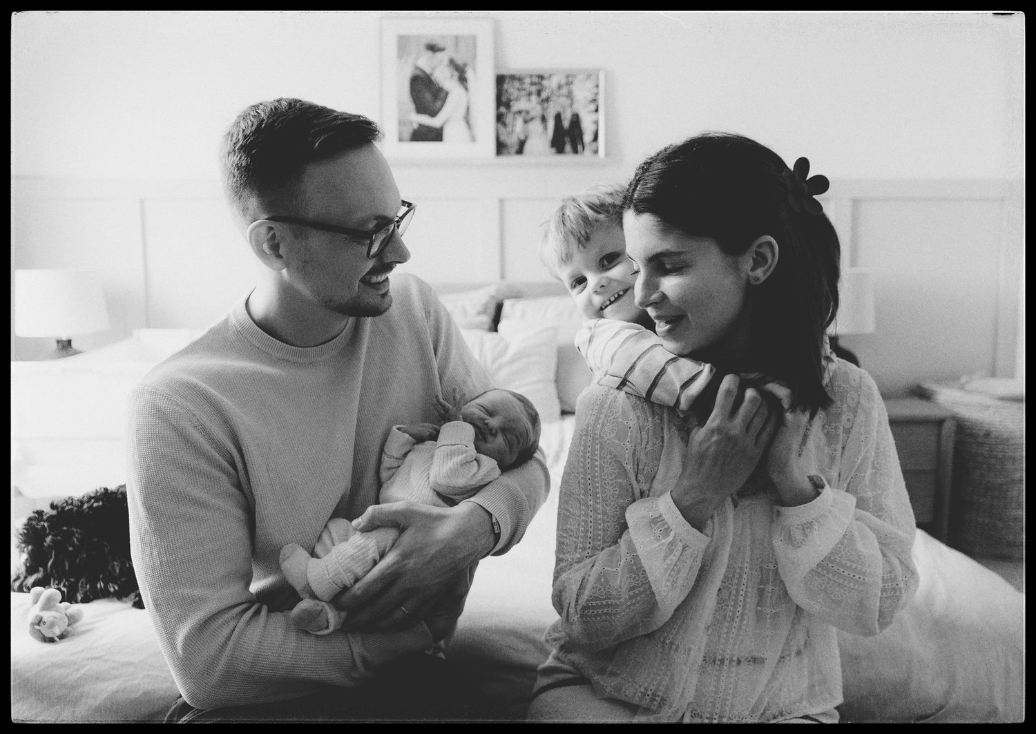 A vintage black and white photograph showing a couple in their home with a newborn baby.