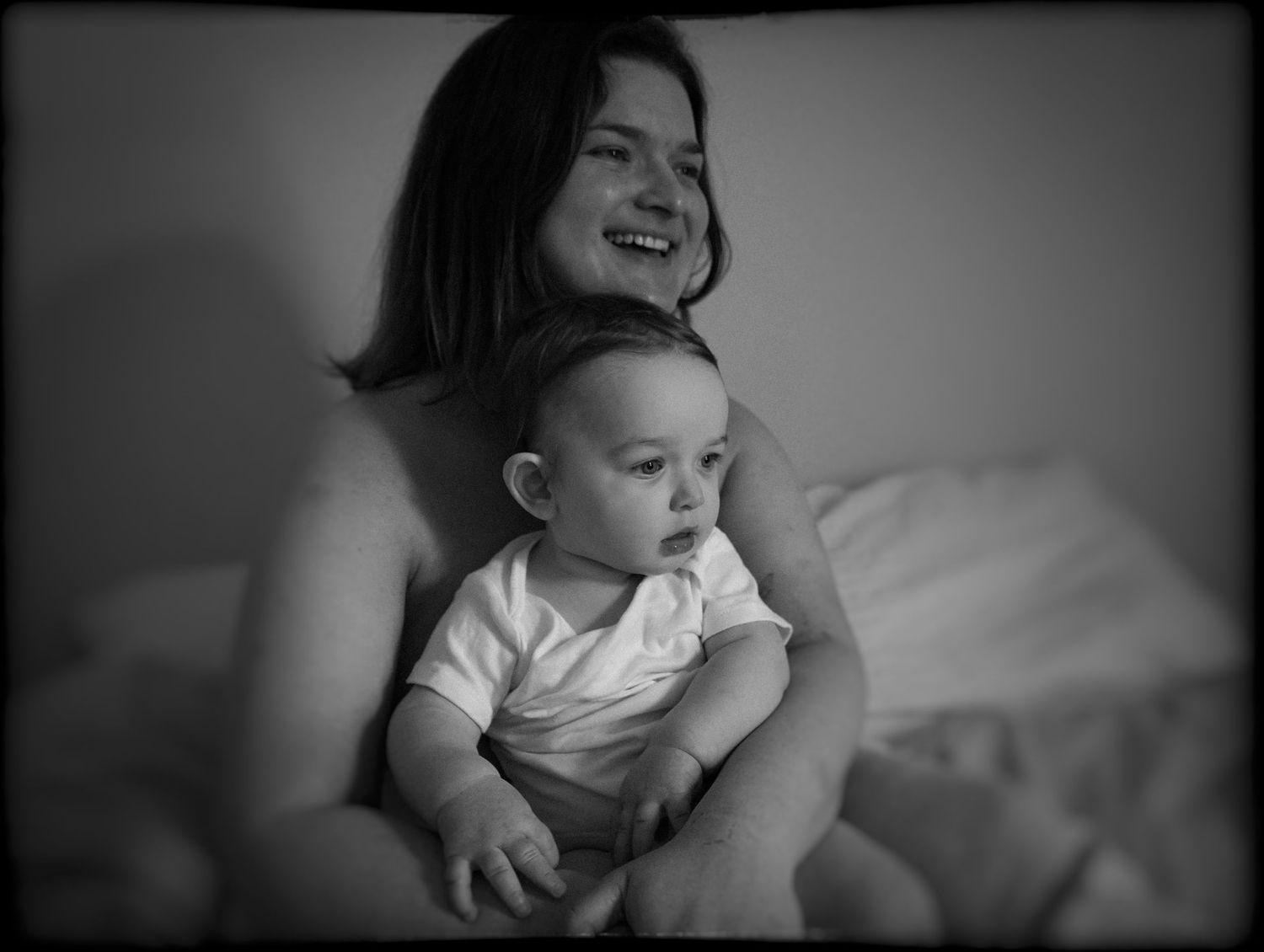 Candid black and white indoor portrait of parent and infant sharing a tender moment.