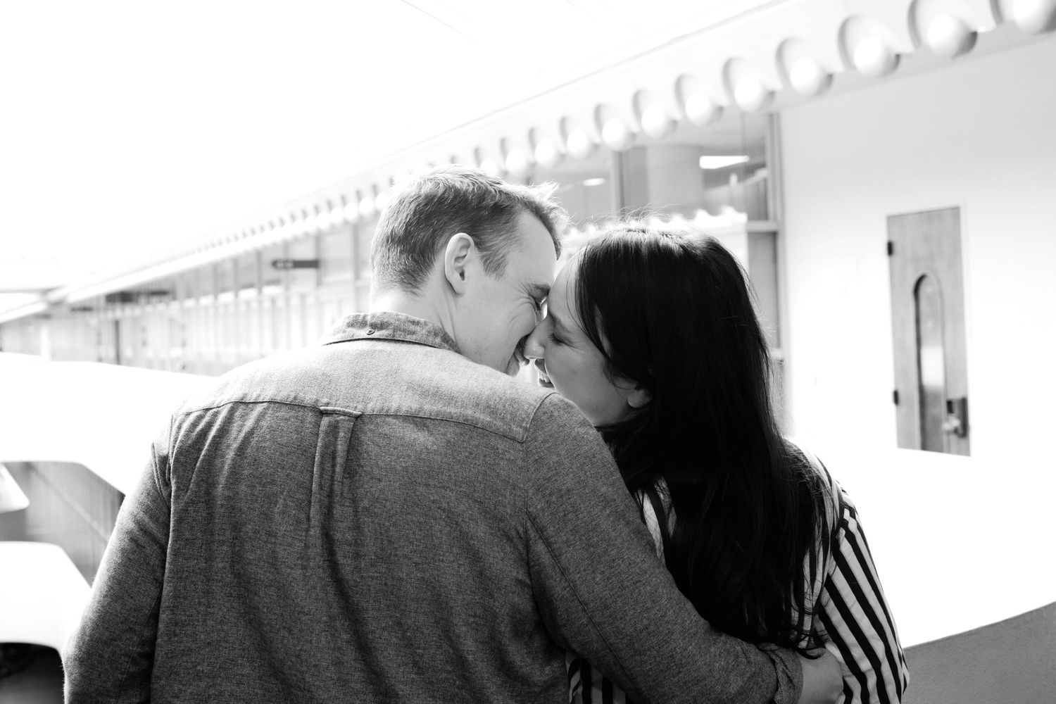 a black and white photo of a happy couple recently engaged, kissing at the balcony of the marin county civic center