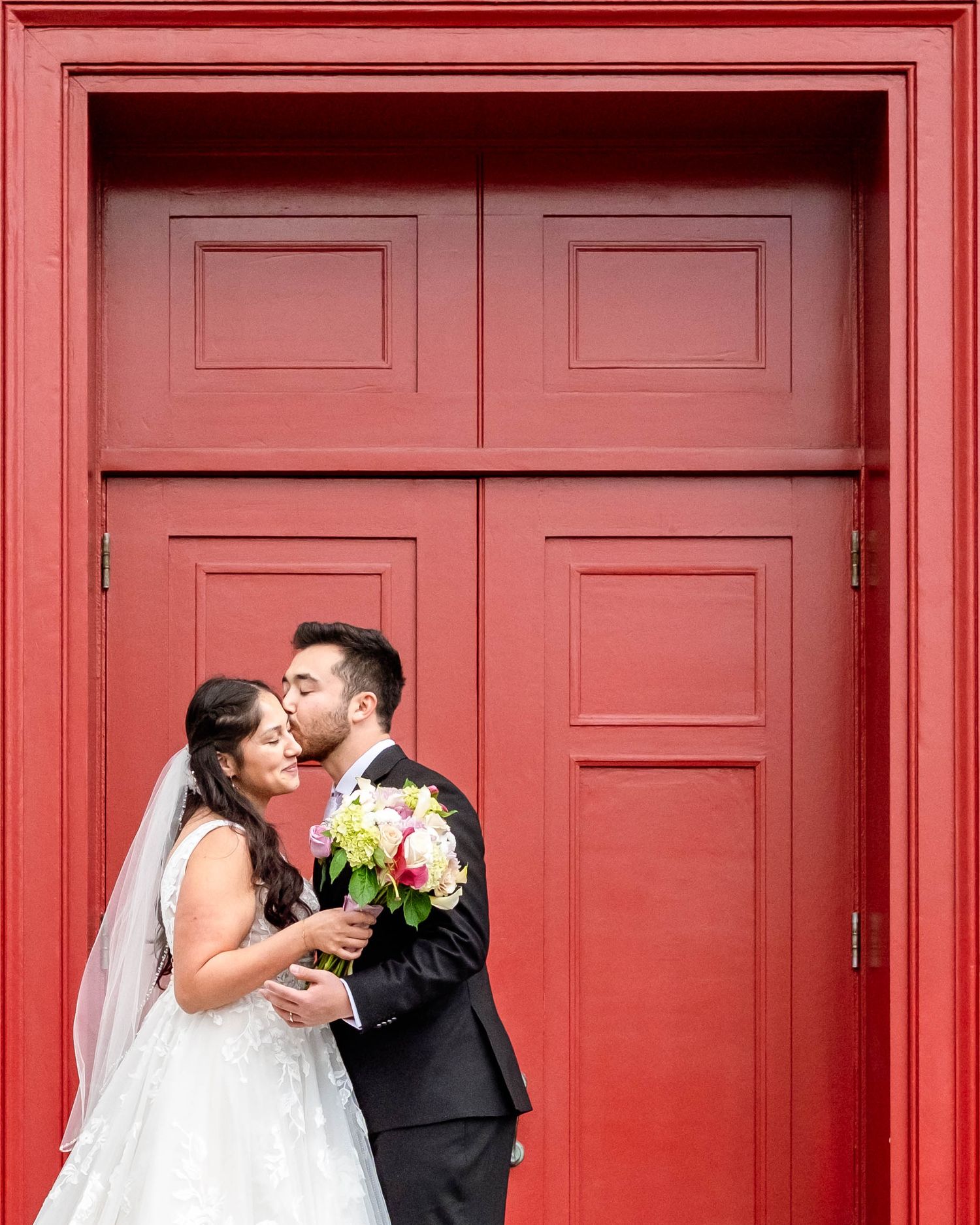 a happy bride and groom kissing in front of a church door after getting married
