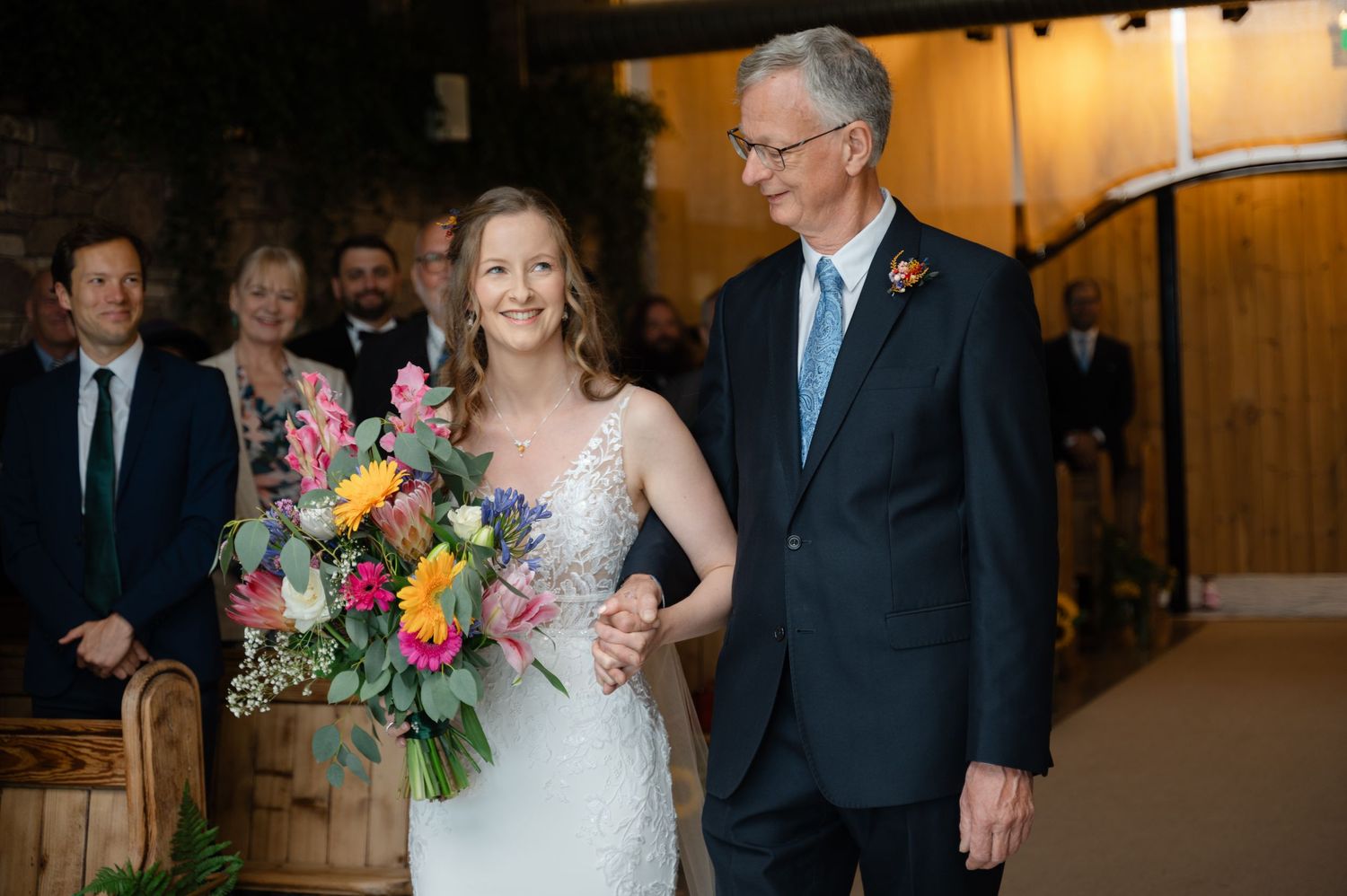 Bride and her father standing at the beginning of the aisle, holding hands and smiling