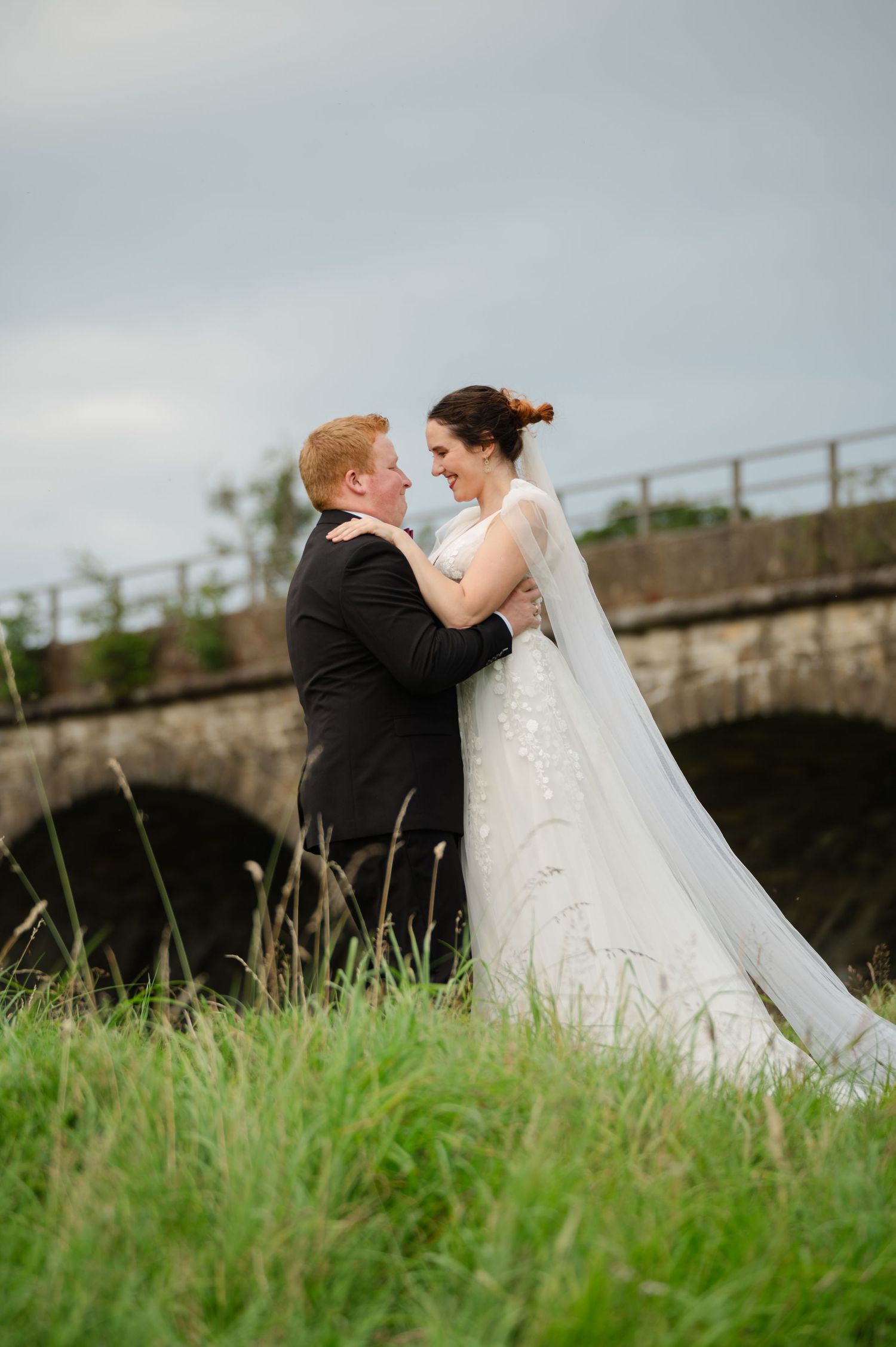 Groom lifting the bride playfully in a grassy field