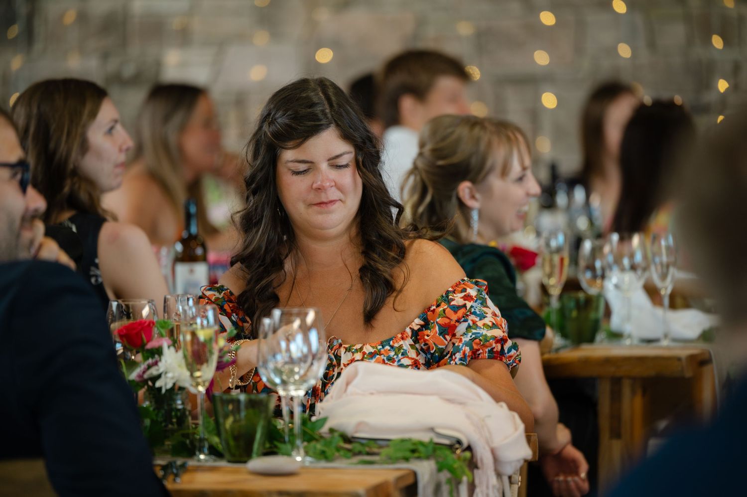 Wedding guest smiling during reception dinner with fairy lights in background