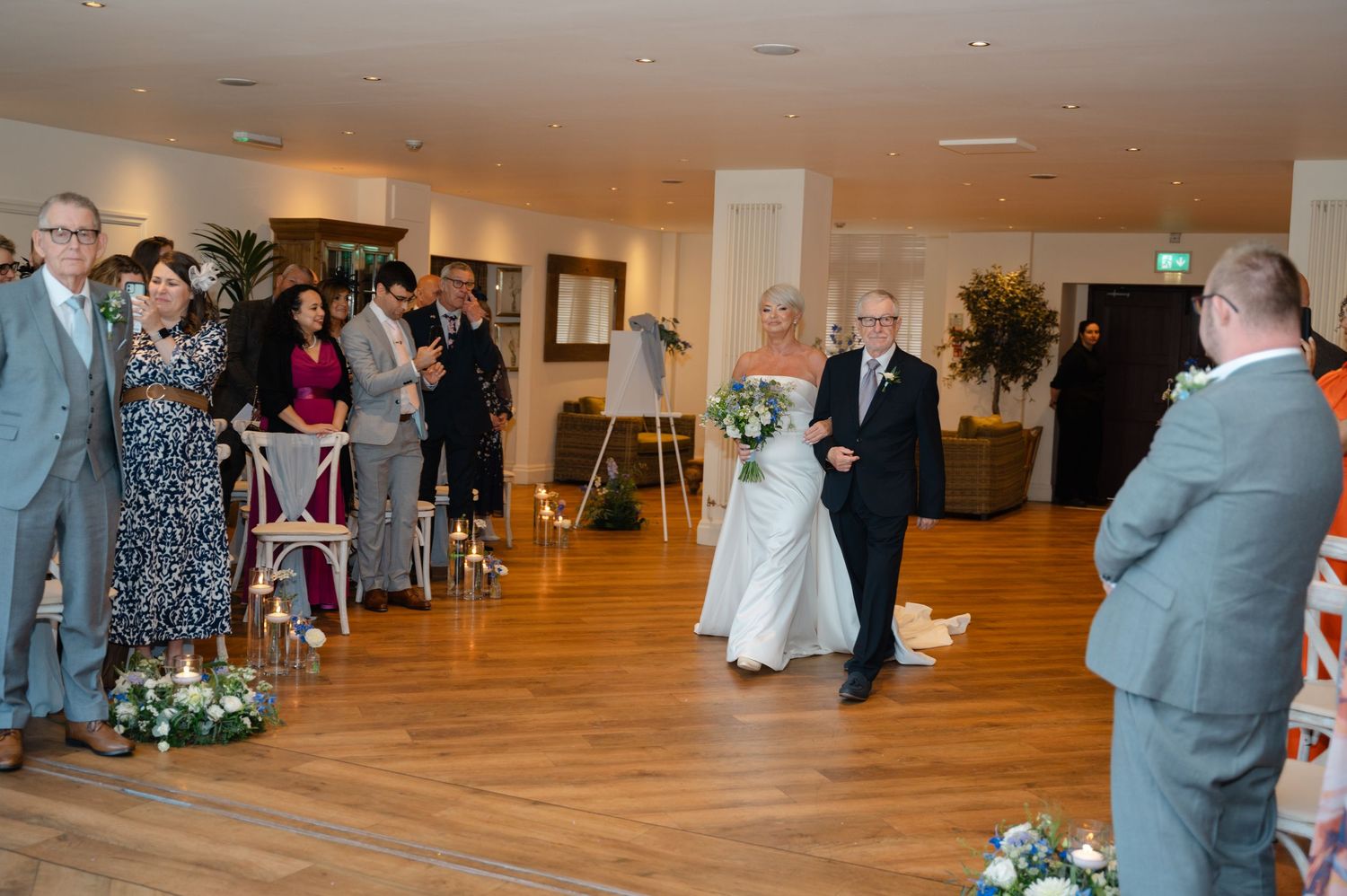 Bride and groom walking down the aisle in an indoor venue surrounded by applauding guests