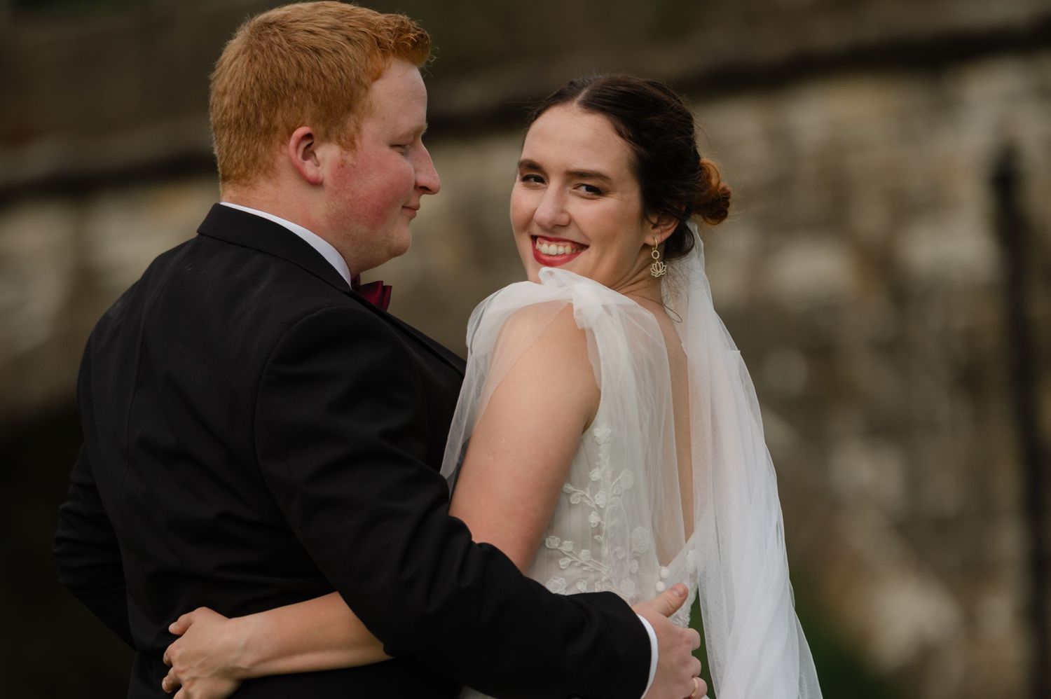 Groom looking at bride lovingly as she smiles back, captured in a candid moment