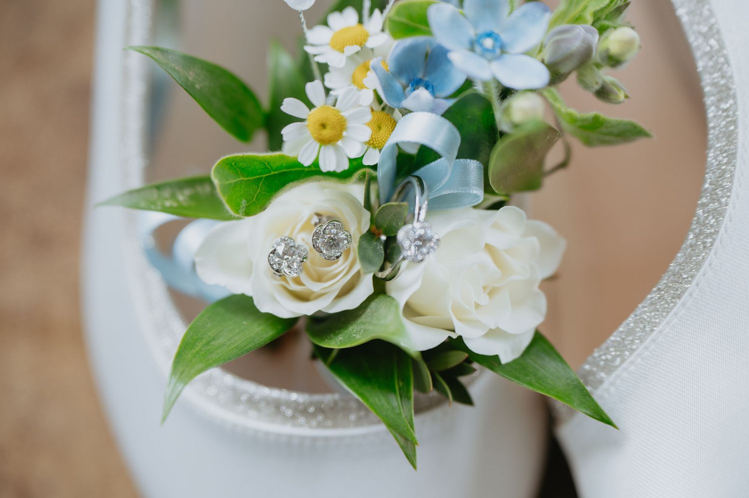 Bridal bouquet with white roses, daisies, and greenery arranged inside a heart-shaped wicker decoration, styled for a romantic flat lay.