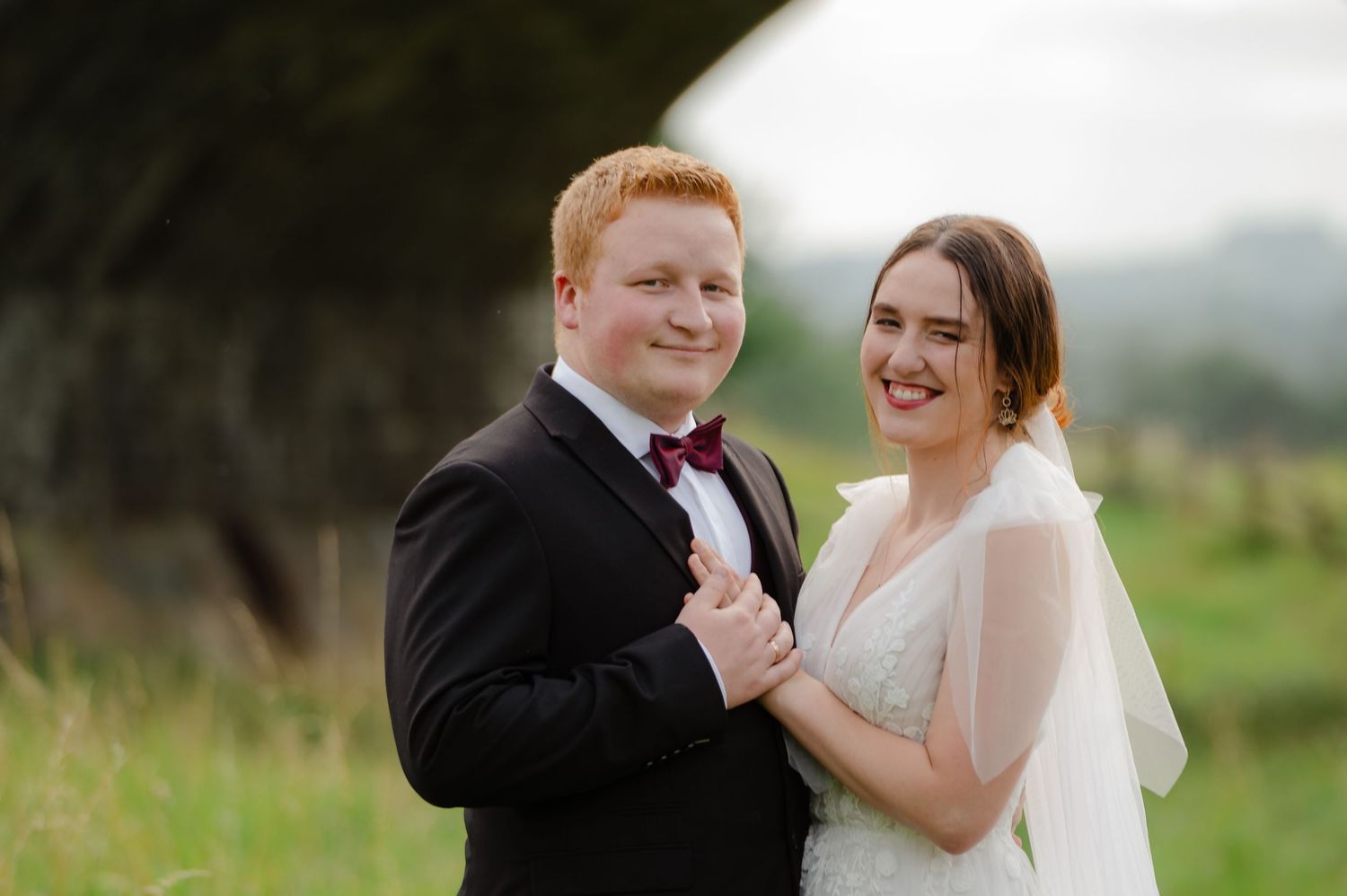 Bride and groom smiling together in a field during golden hour