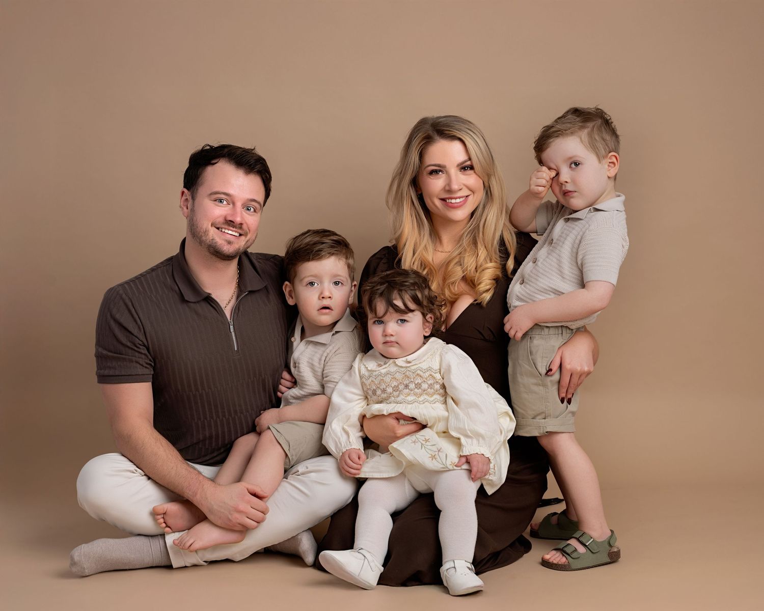 Family portrait during a studio family photoshoot in Lancashire with parents and three young children wearing neutral coordinated outfits