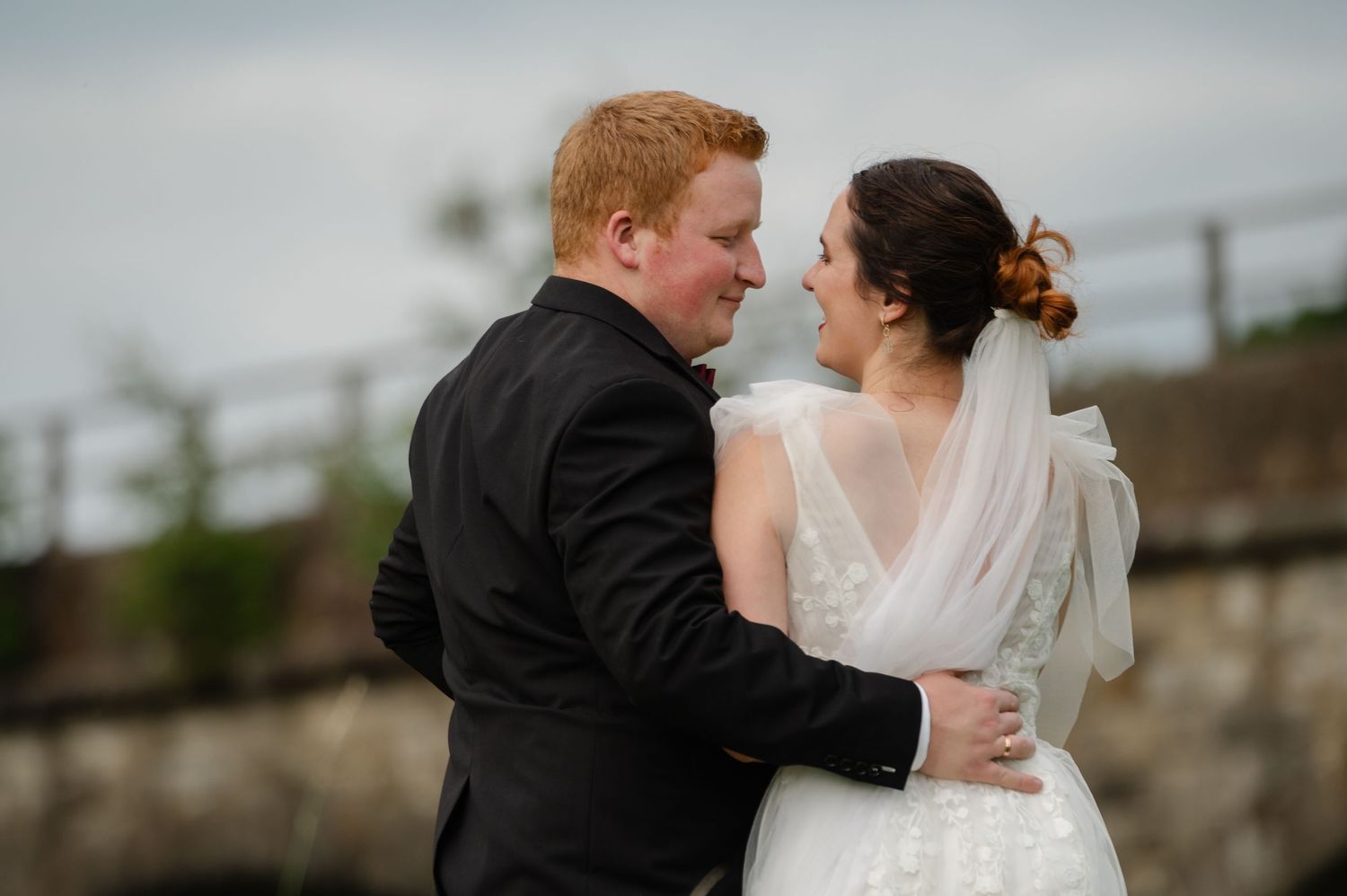 Bride and groom embracing with a scenic countryside view behind them