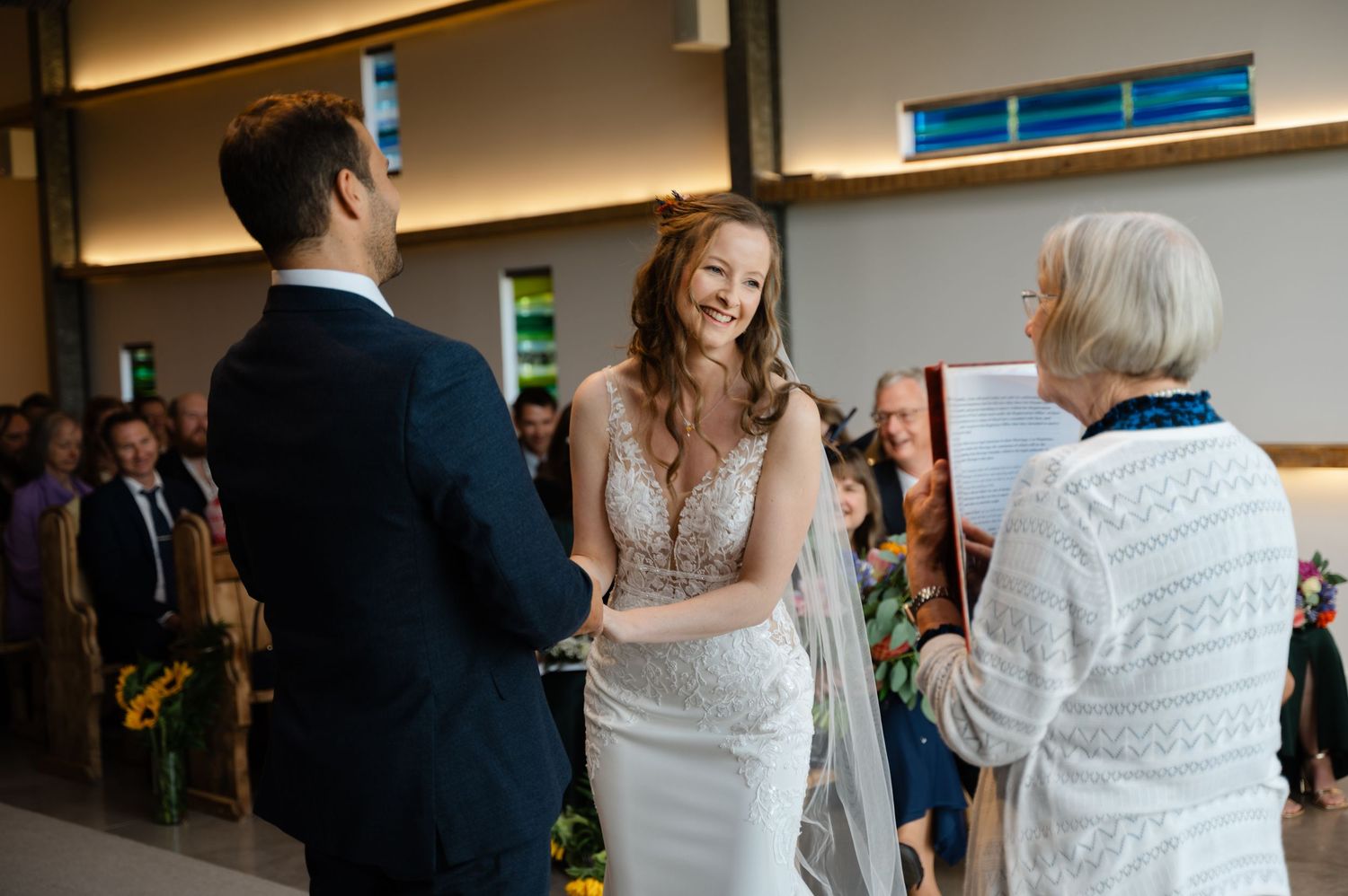 Bride smiling as she greets the wedding officiant inside the ceremony venue