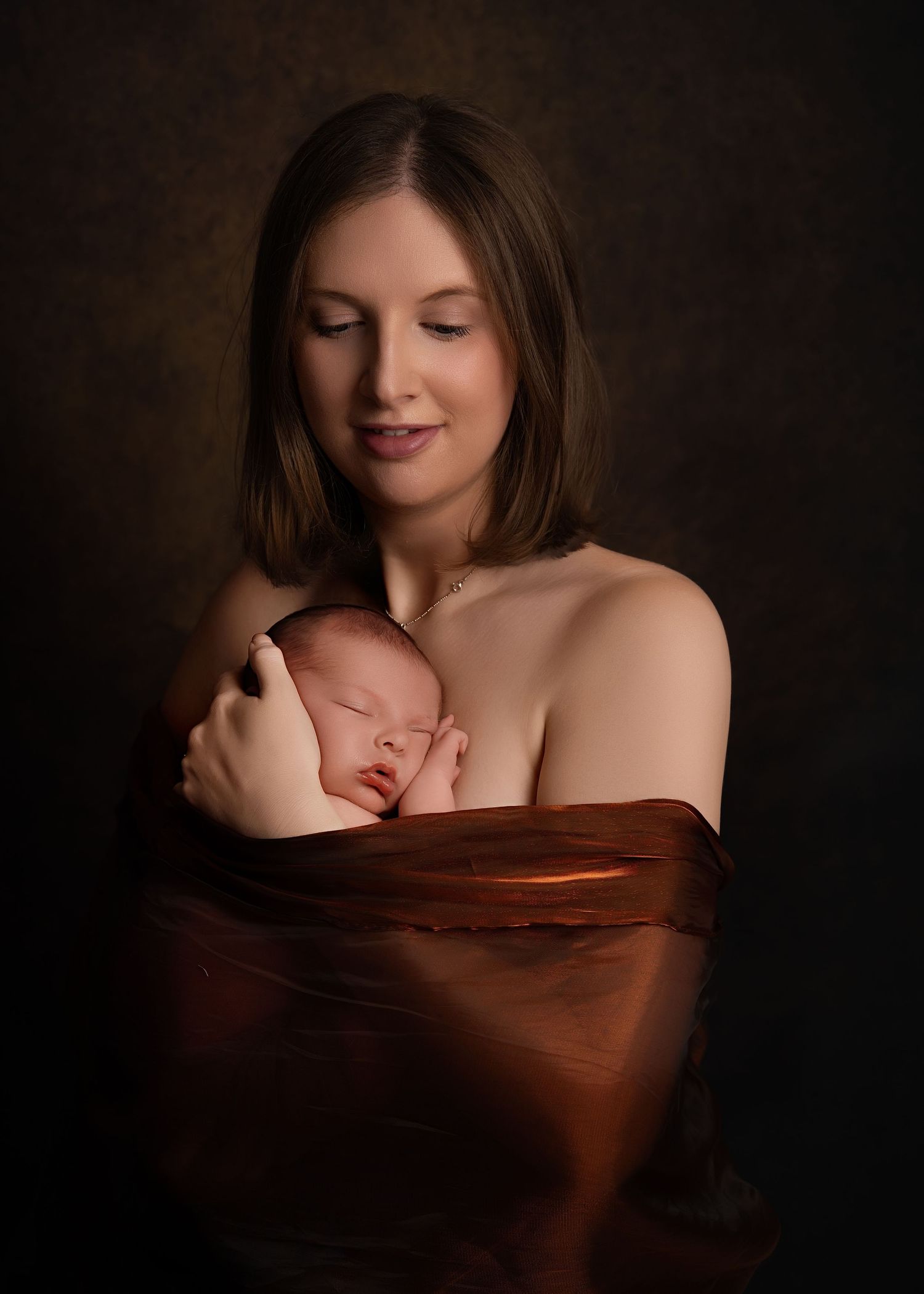 Mother wrapped in a dark shawl, gently holding her sleeping baby against her chest with a peaceful expression.