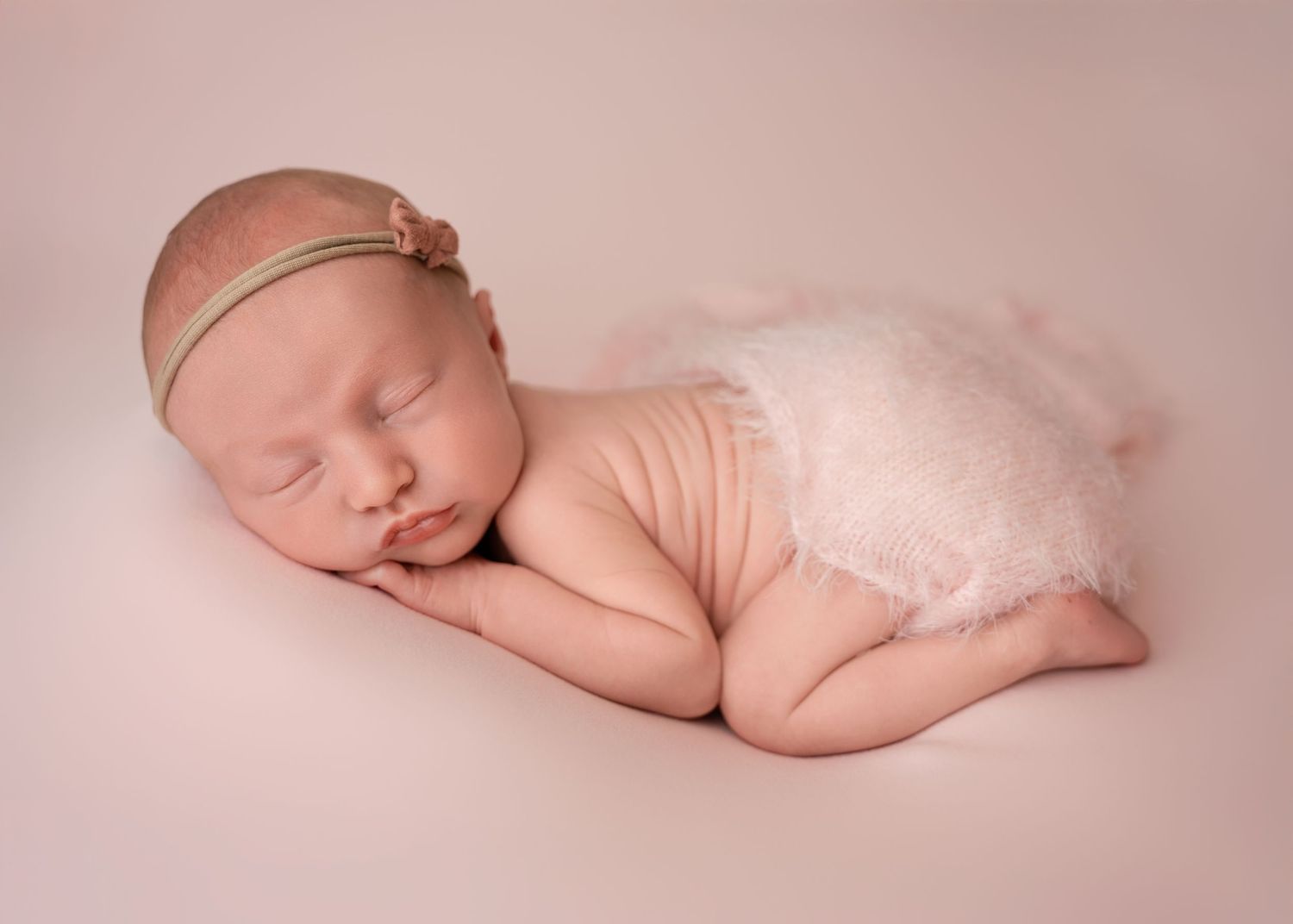 Newborn baby sleeping curled up on a soft blanket