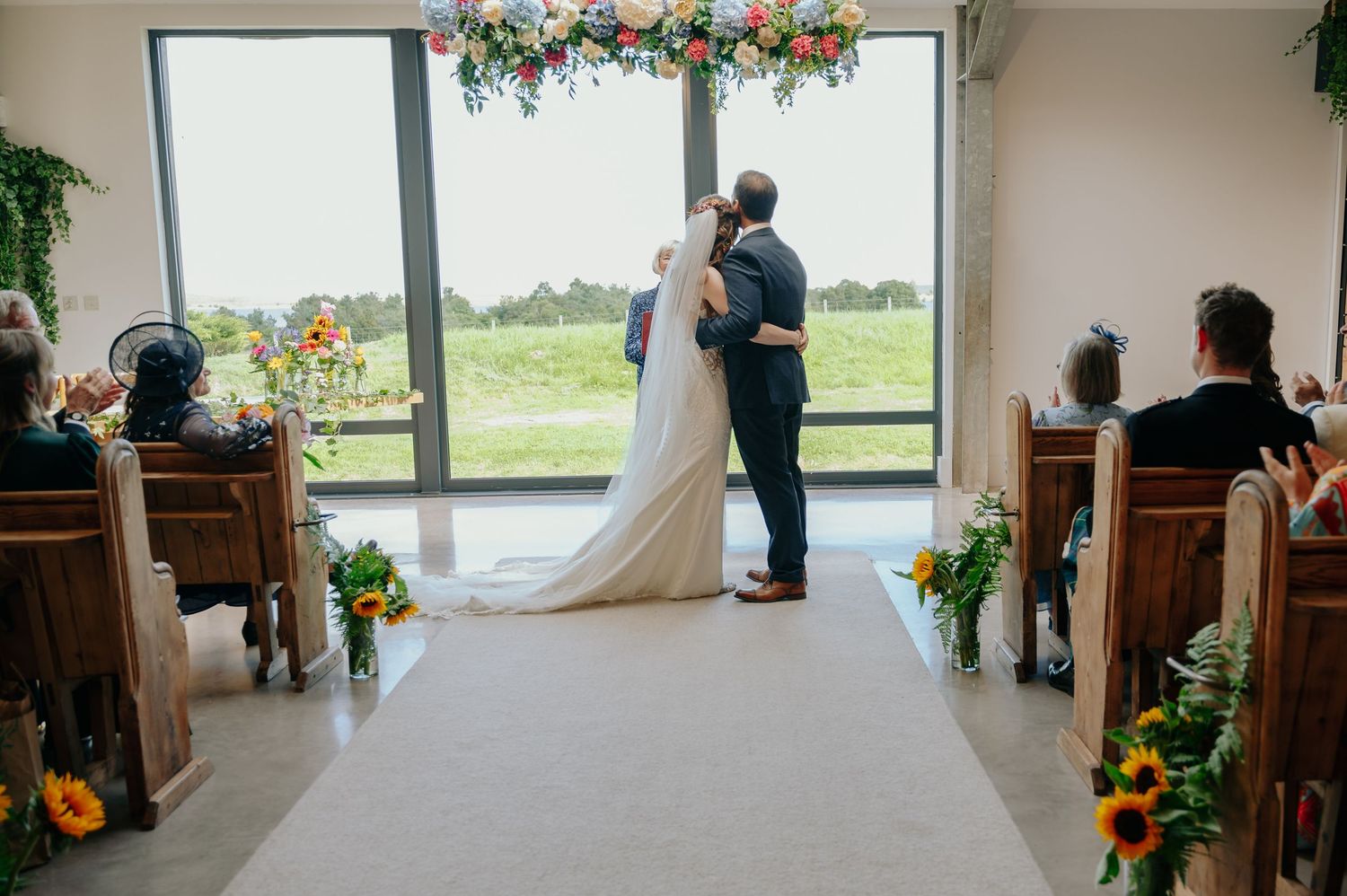 Bride and groom standing at the altar holding hands in a bright, airy ceremony space