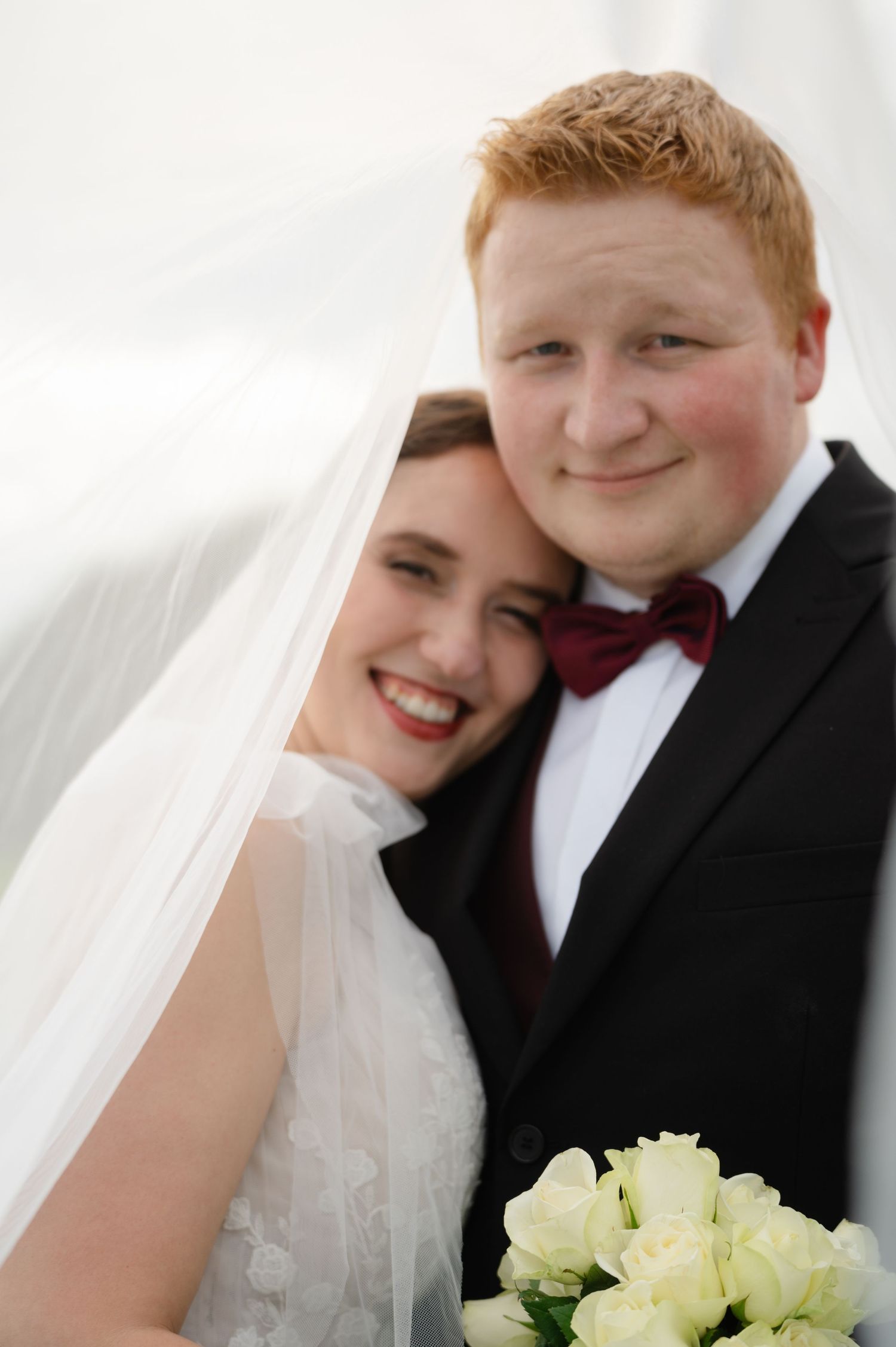 Close-up of bride leaning into groom, both smiling with joy