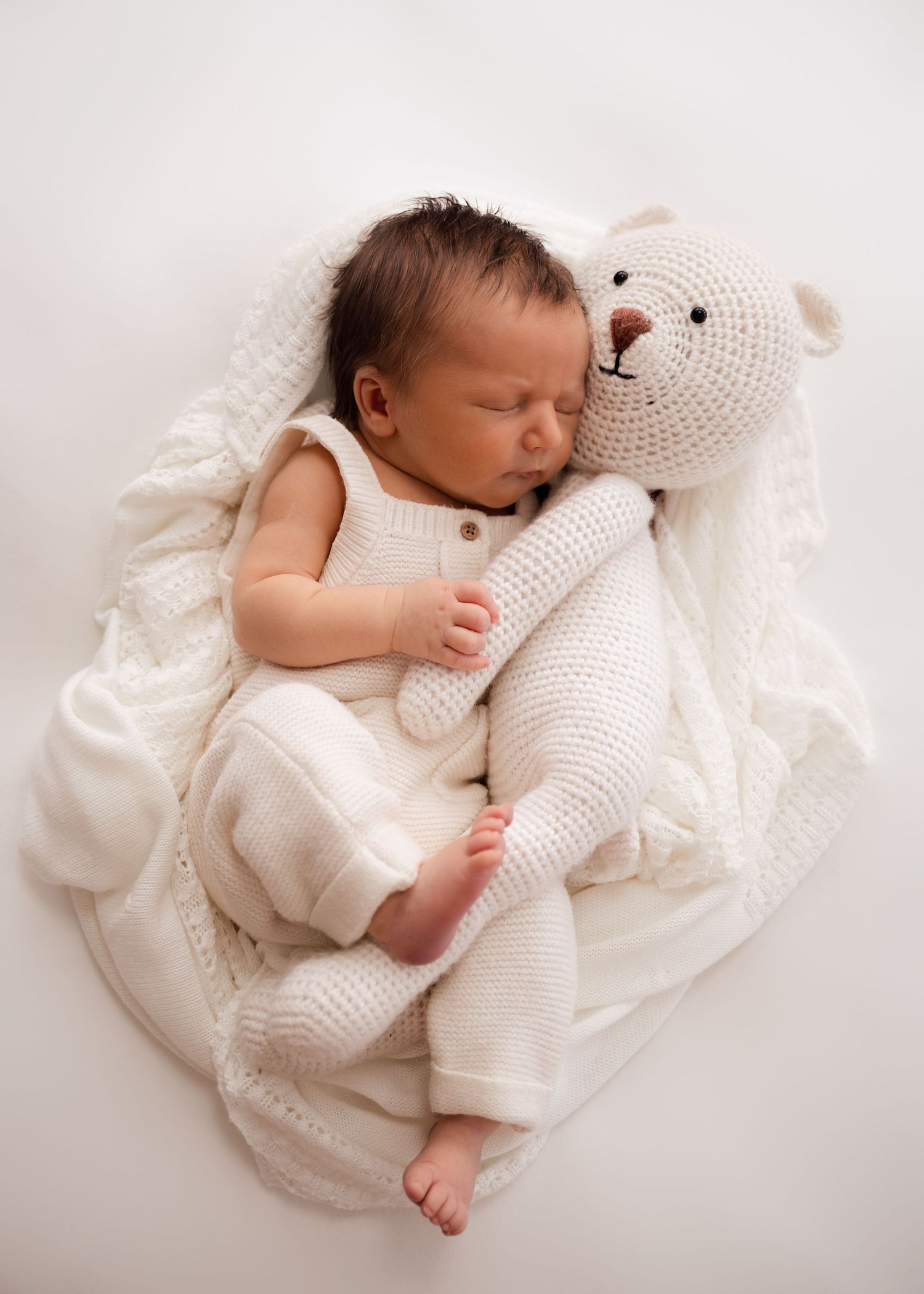 Newborn baby sleeping wrapped in a white blanket during an at-home session
