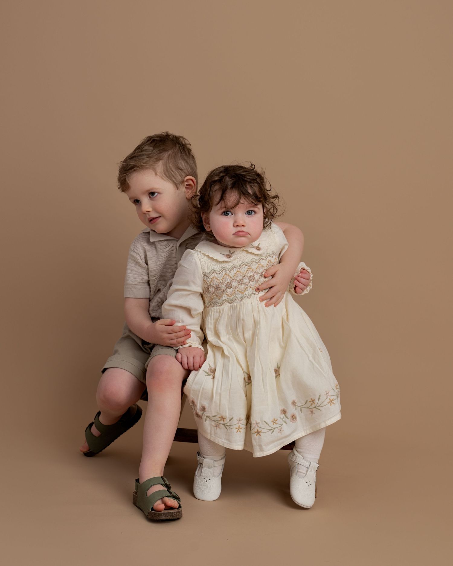 Brother and baby sister sitting together during a sibling portrait at a Lancashire family photography studio