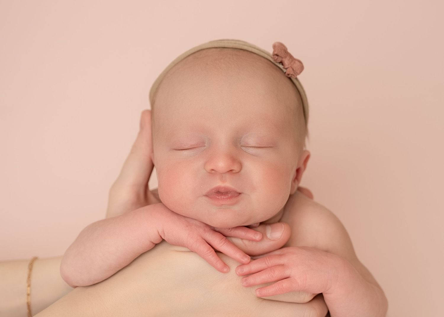 Peaceful newborn resting with hands tucked under chin.