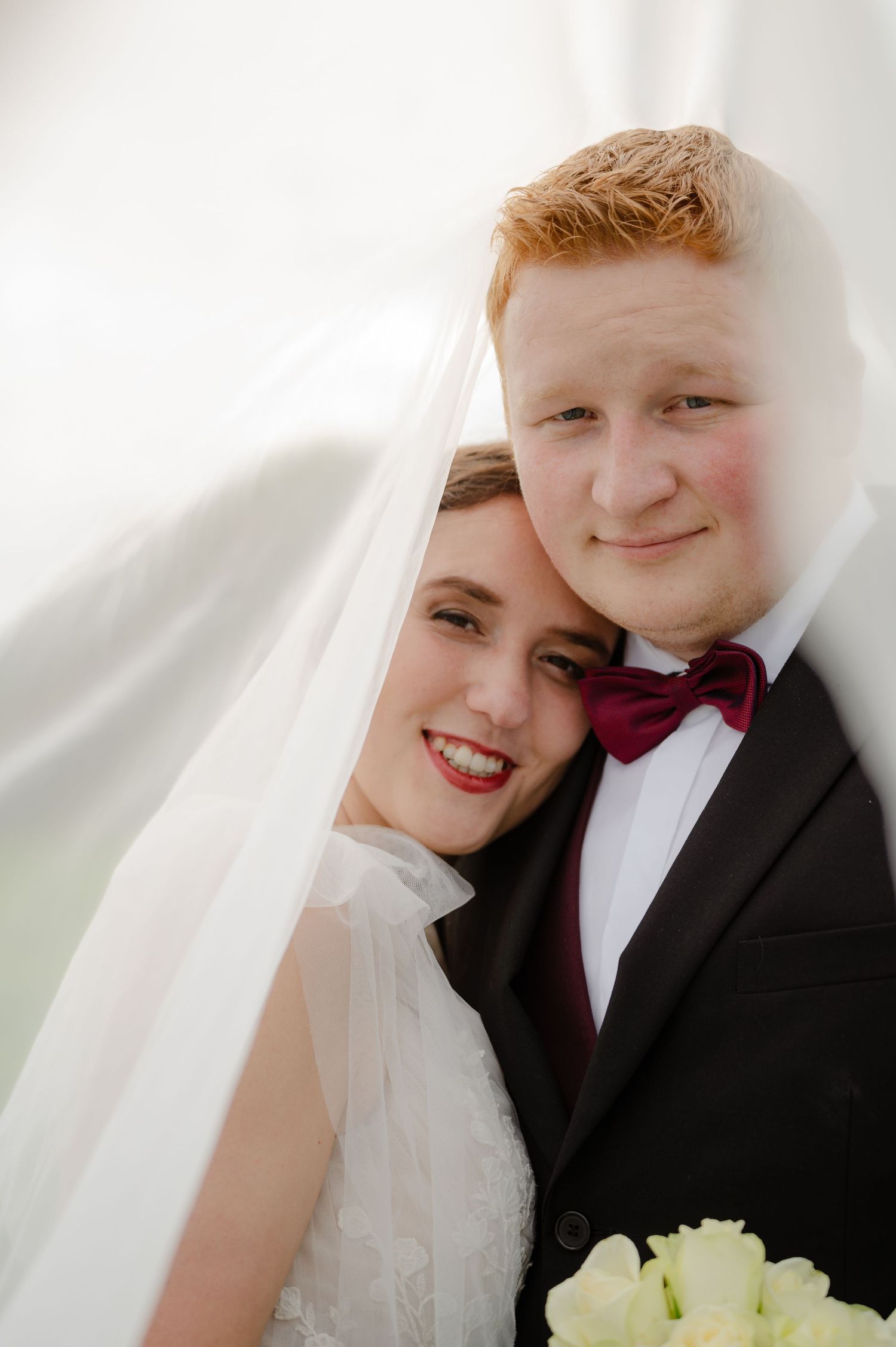 Bride and groom smiling under the bride’s veil on their wedding day