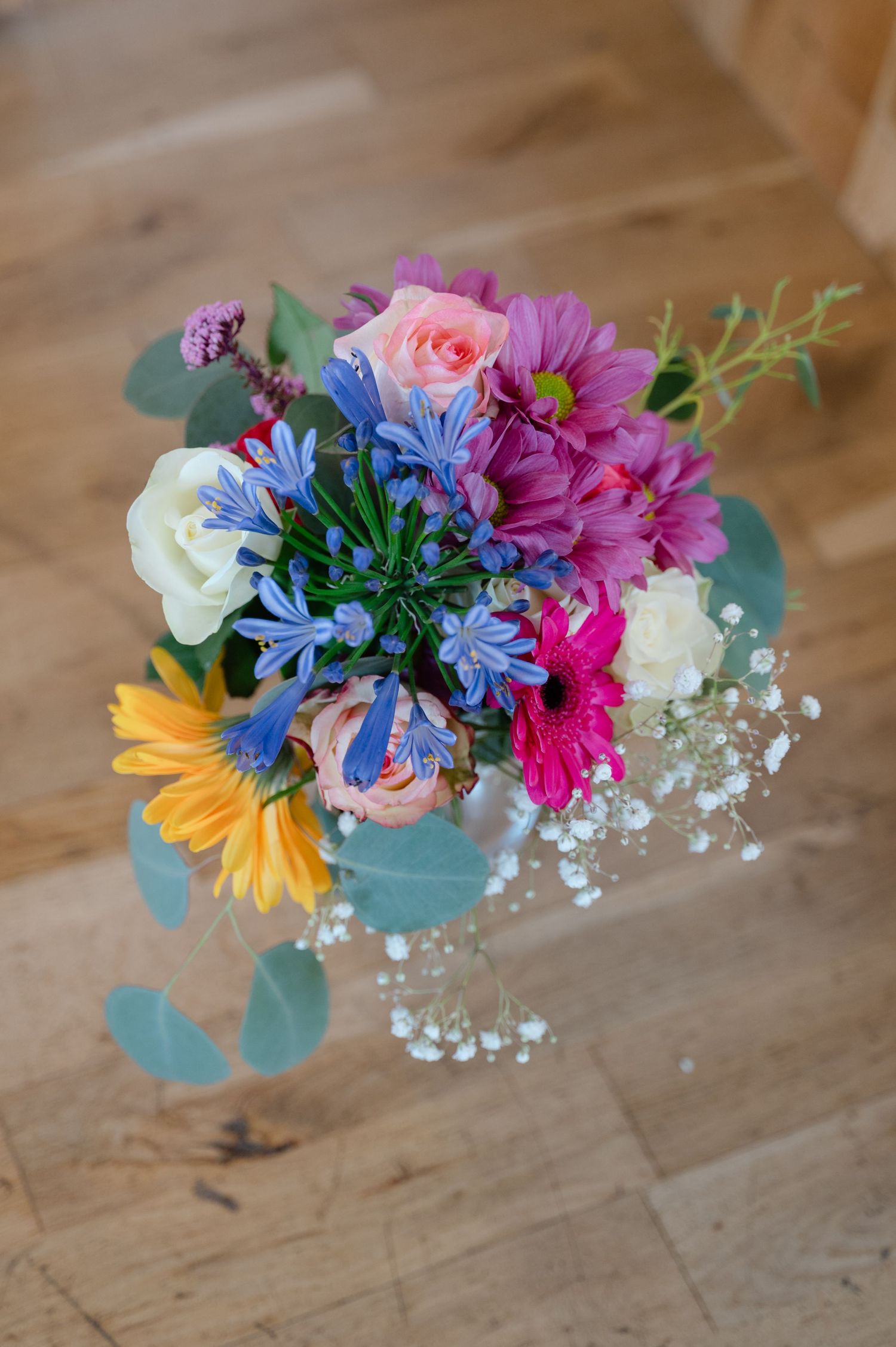 Close-up of a colourful bridal bouquet placed on a rustic wooden table