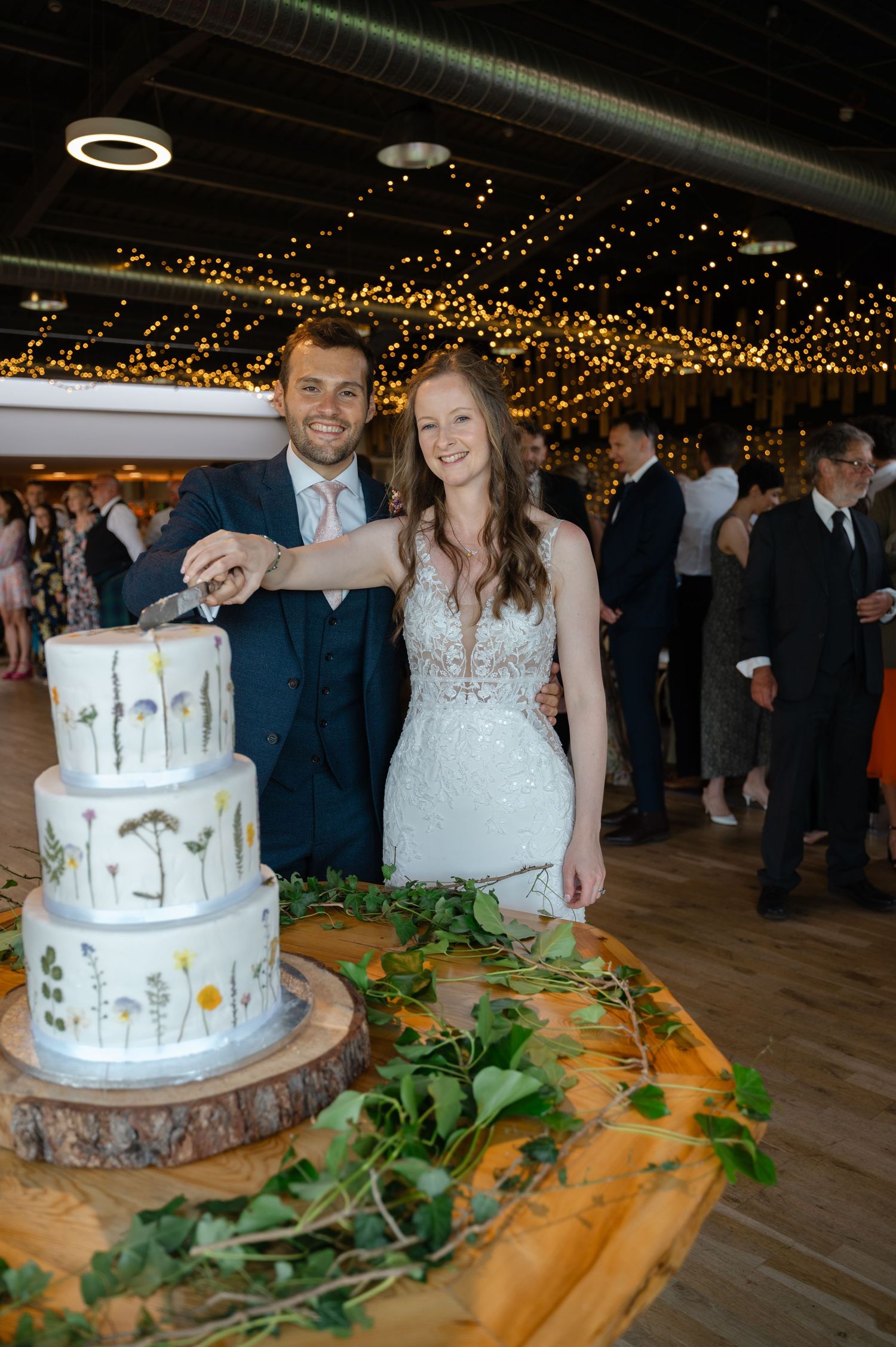 Bride and groom cutting a tiered wedding cake at indoor reception
