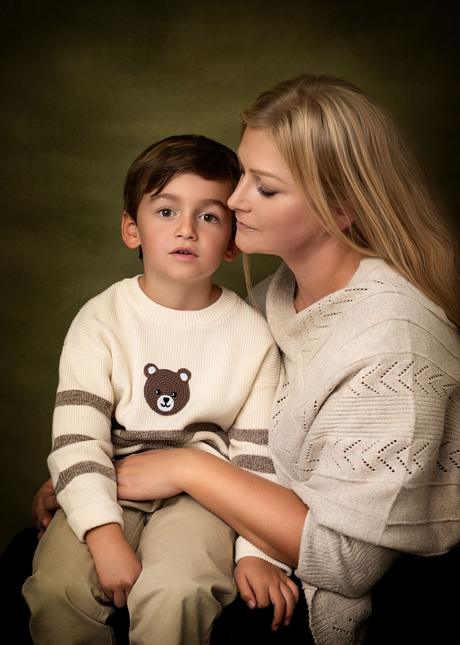 Adult woman holding a young child on her lap, both seated indoors and facing each other.