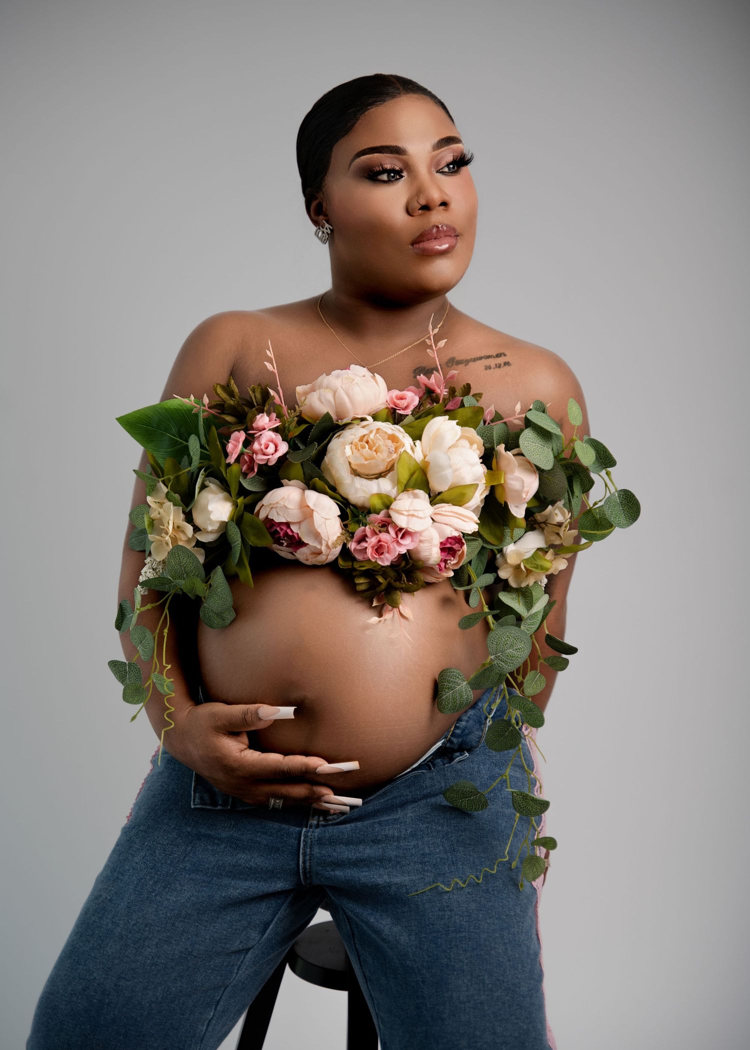 Pregnant woman sitting on a chair in a white top during maternity session