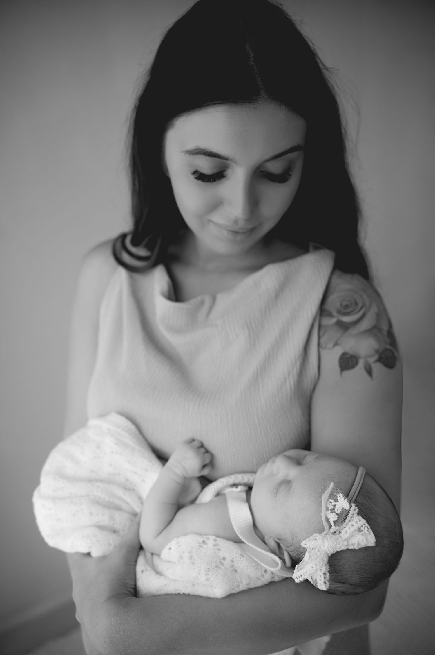 Black and white portrait of a mother gazing down lovingly at her newborn baby in an authentic motherhood photography moment.