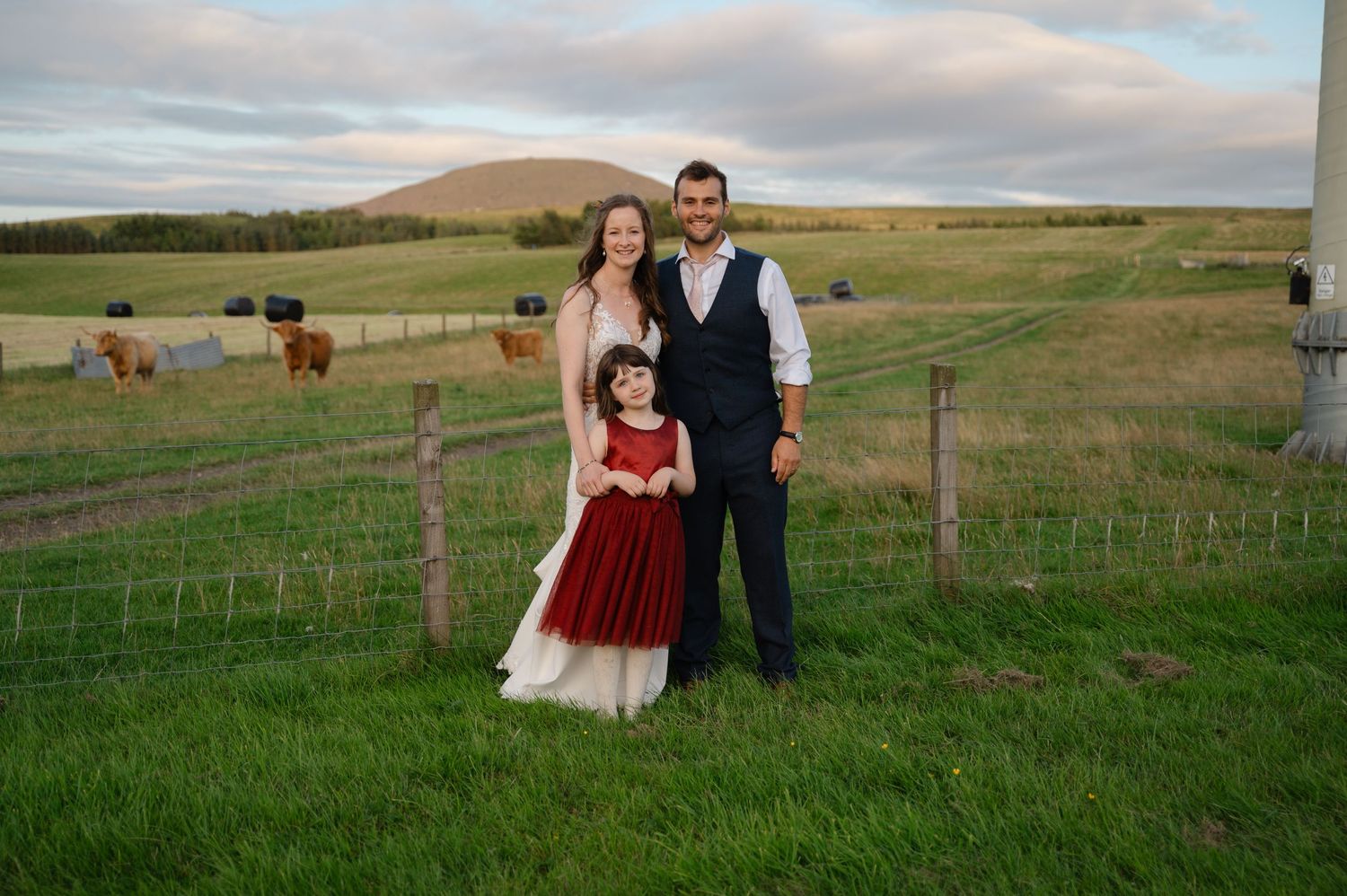 Groom and young girl posing together in a scenic rural wedding location