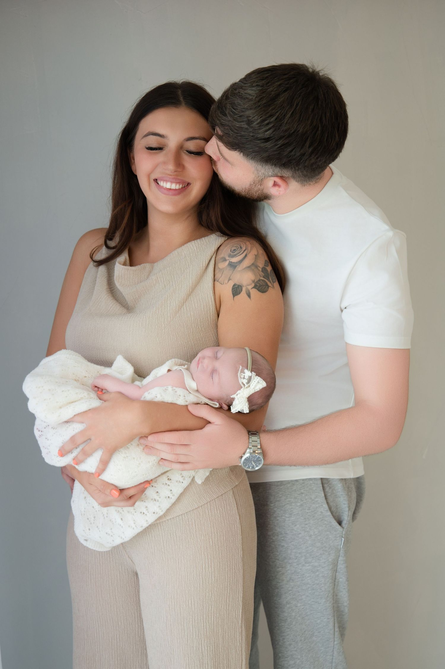 Mother and father holding their newborn baby during a soft, intimate lifestyle photography session, capturing a tender family connection