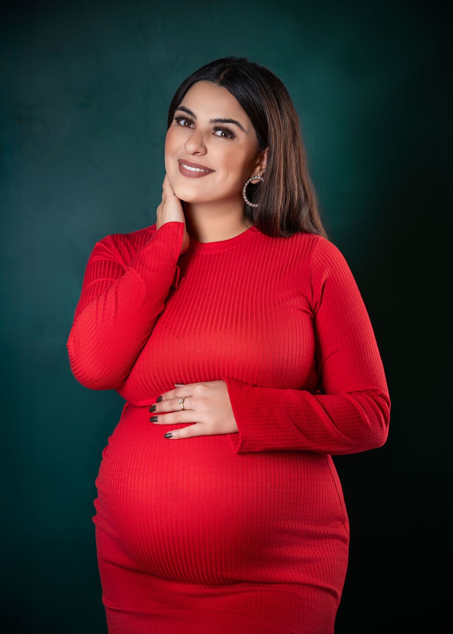 Pregnant woman in a red dress posing for a portrait