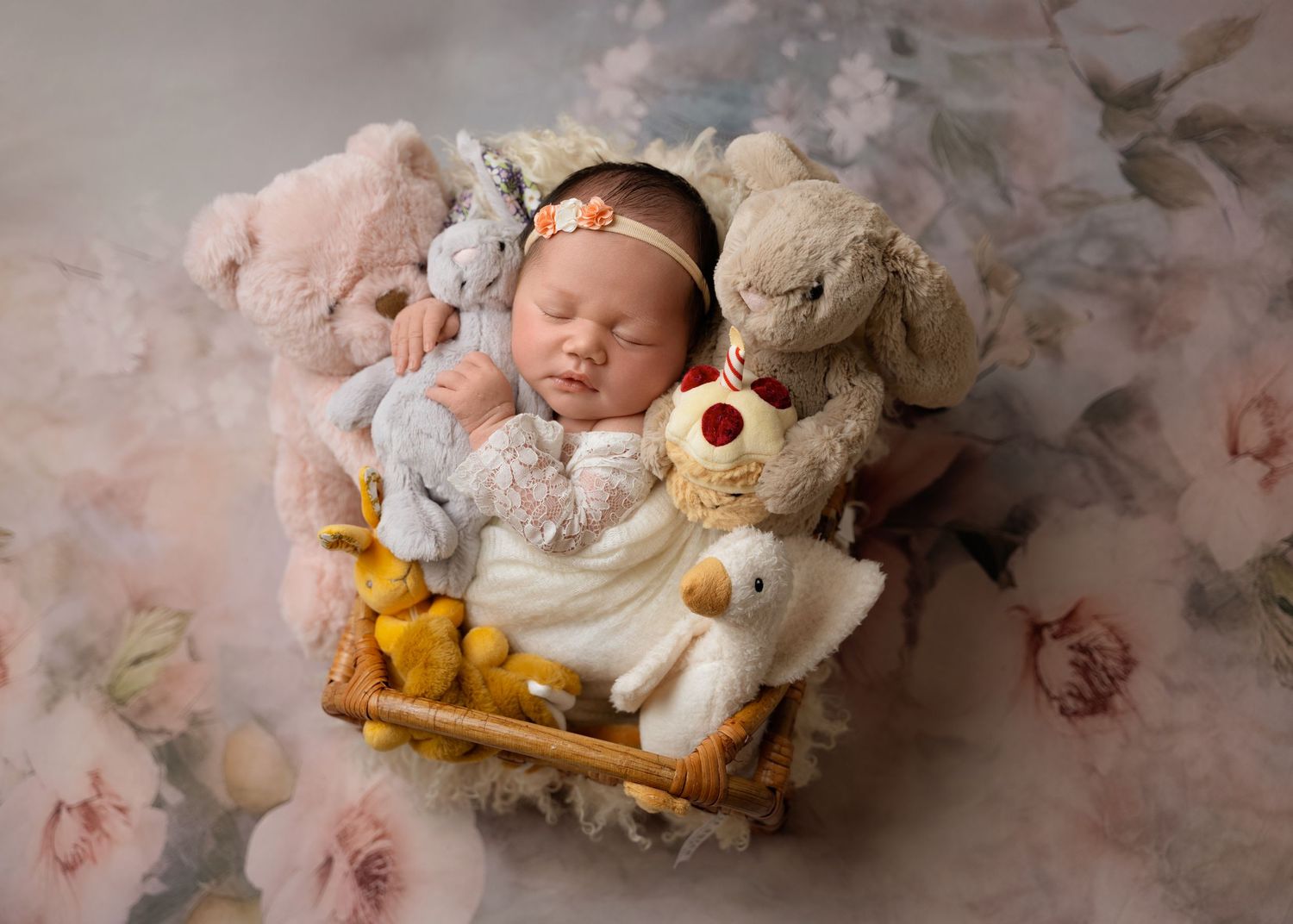 Newborn surrounded by flowers and stuffed animals
