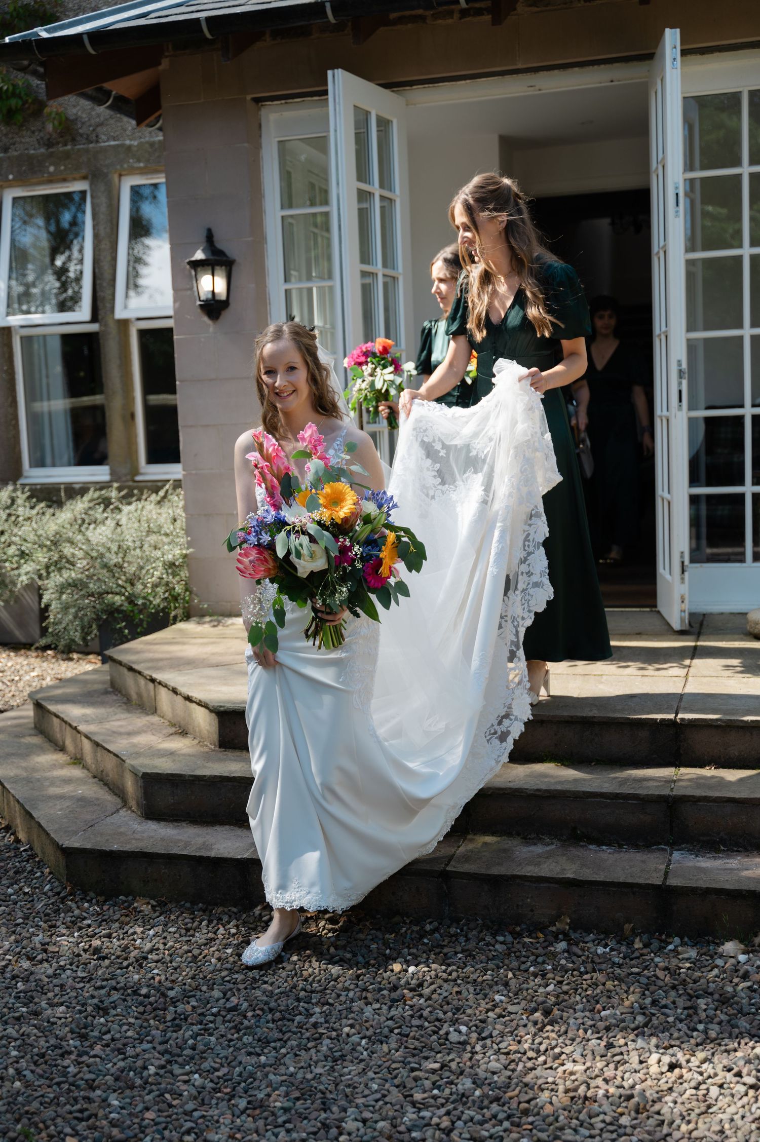 Bride lifting her dress slightly as she walks in front of a countryside venue