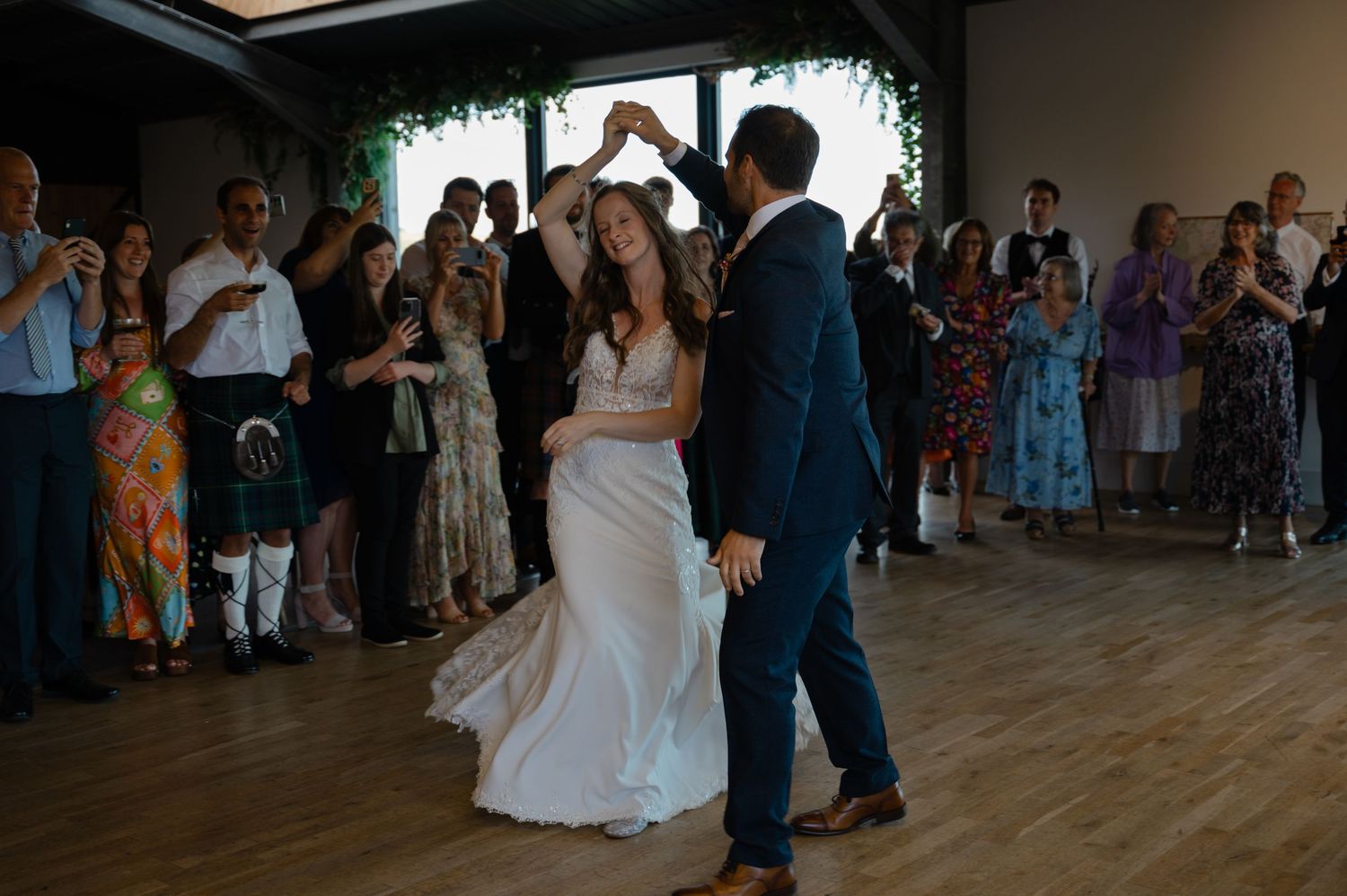 Bride and groom dancing at wedding reception surrounded by guests