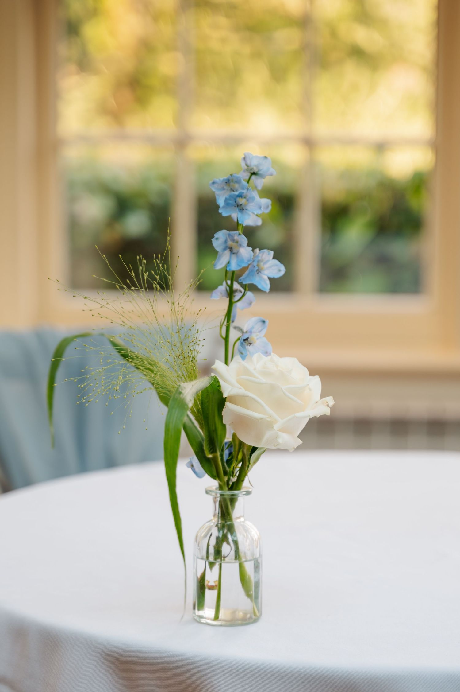Minimalist table decor with single white flower and greenery in a glass bud vase