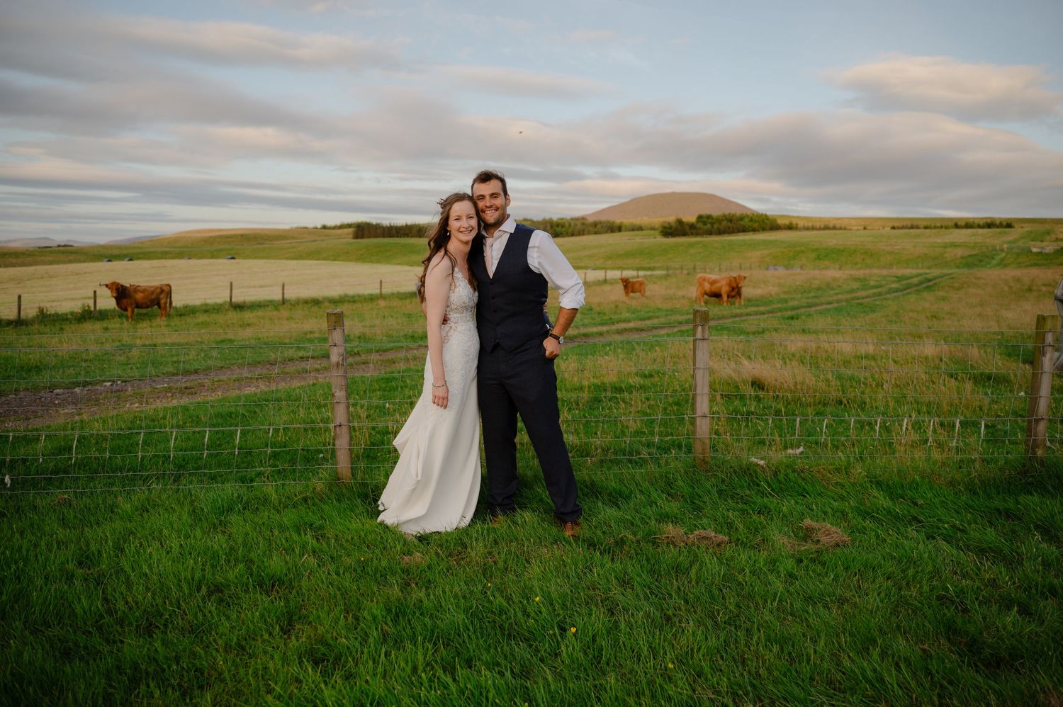 Couple standing together in countryside wedding portrait with scenic backdrop