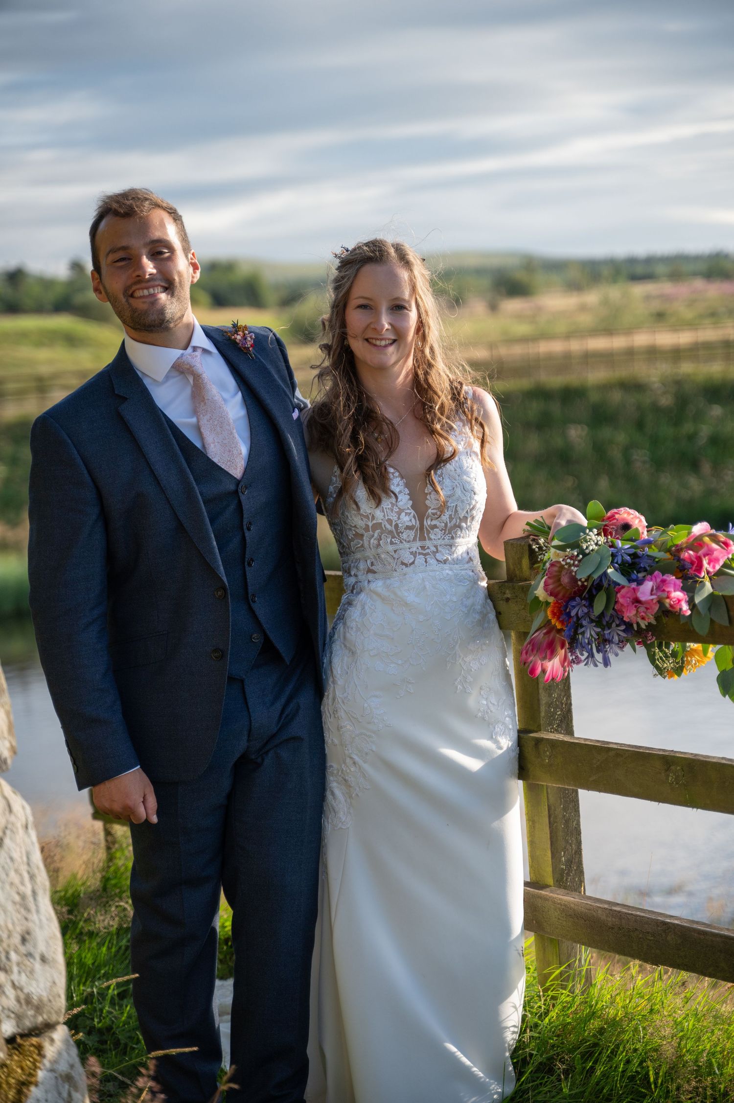 Bride and groom posing with hills and water in the background