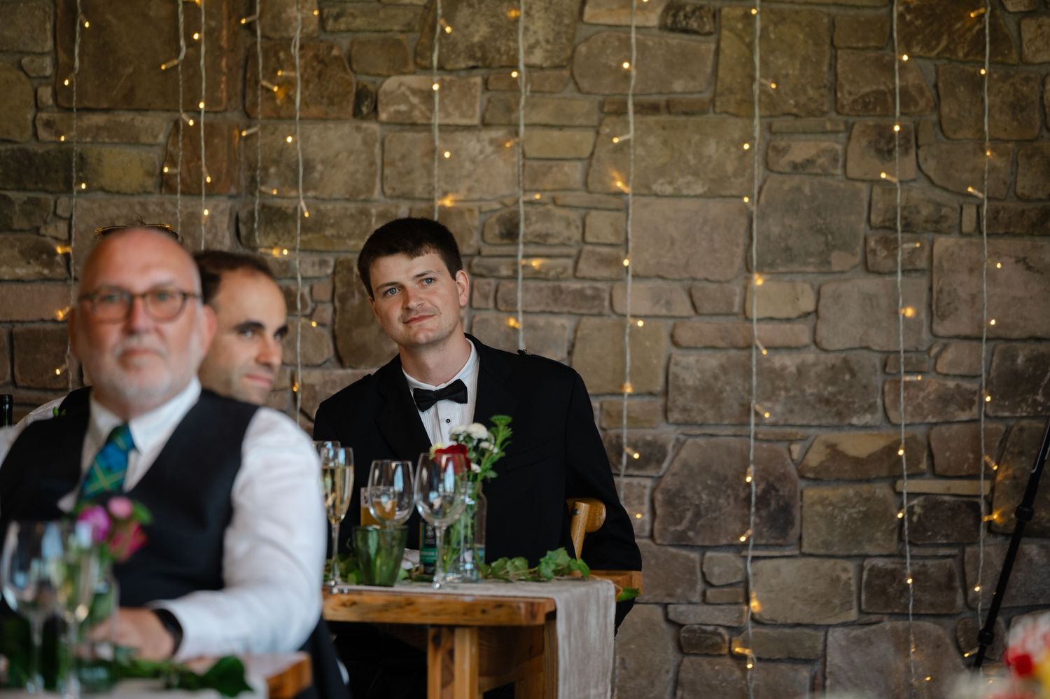 Wedding guest listening intently to speeches with fairy light backdrop