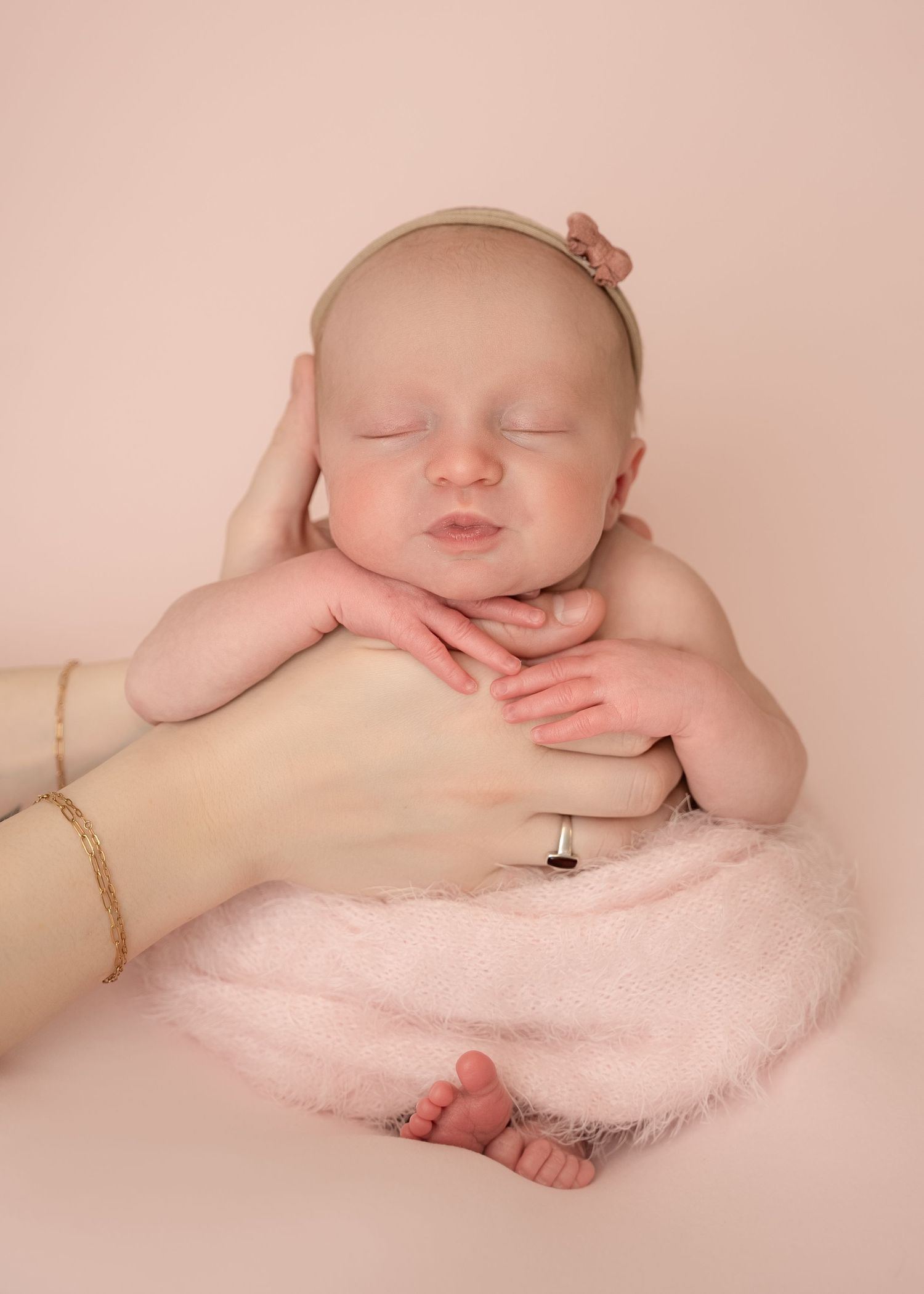 newborn baby in mummy hand on soft pink backdrop