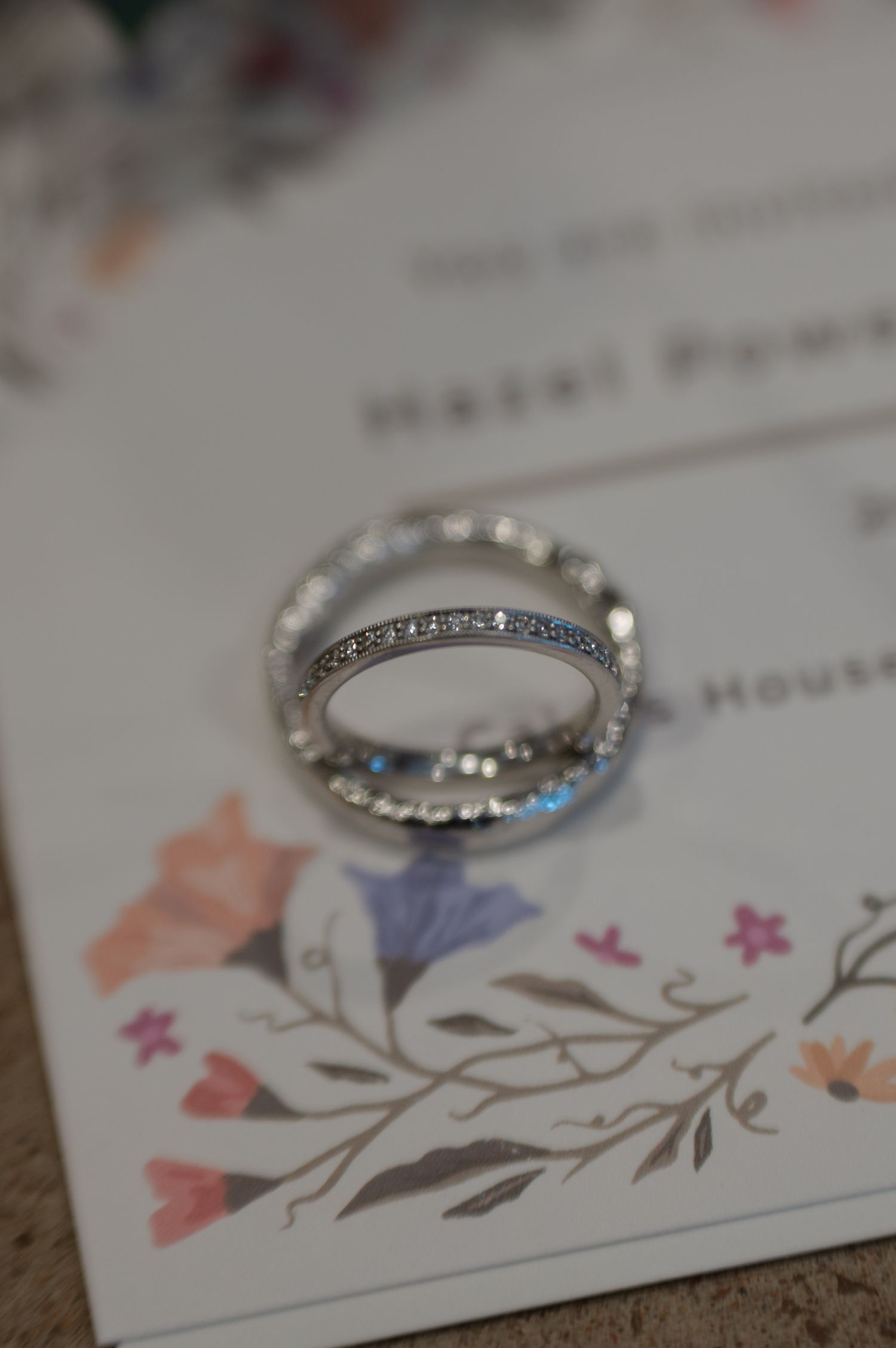 Wedding rings displayed on a floral wedding invitation card
