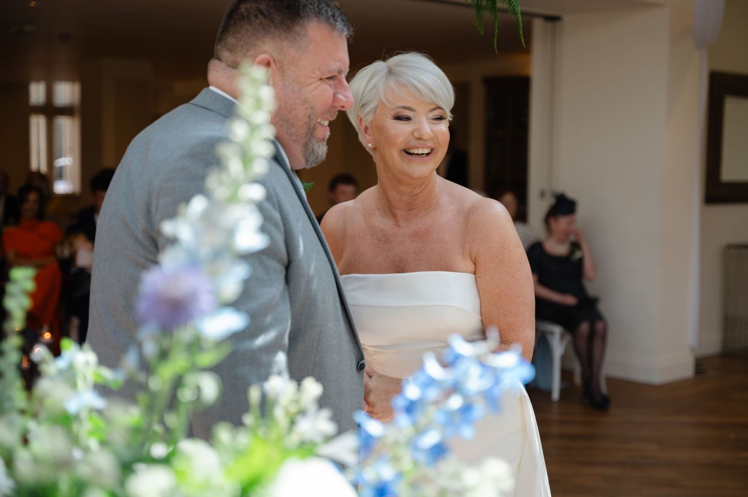 Bride smiling at groom while holding a pastel blue bouquet in an indoor venue