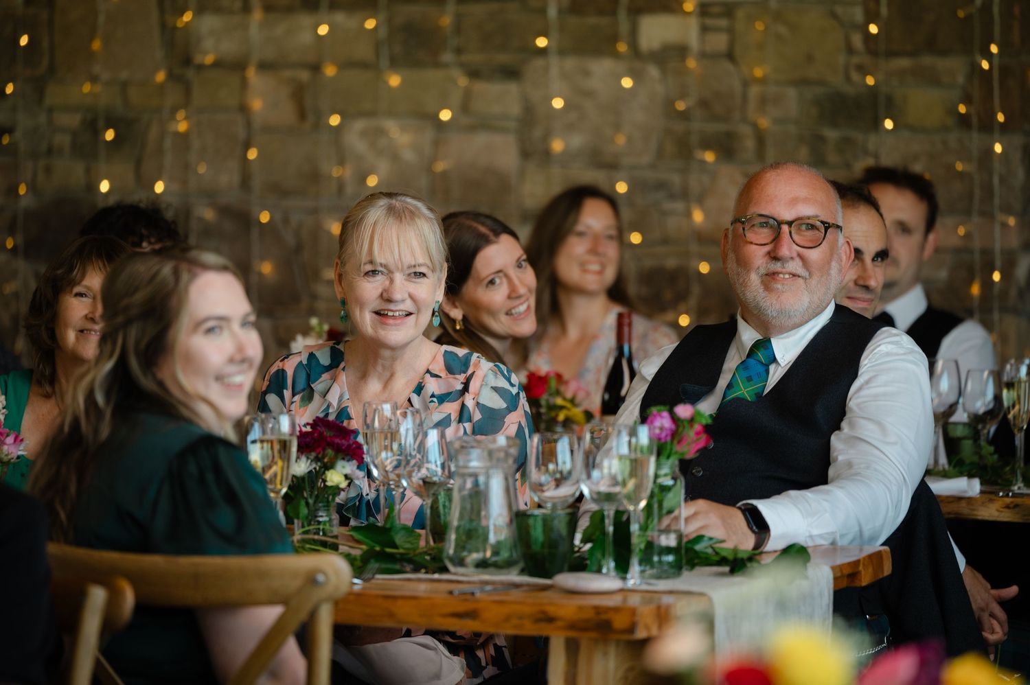 Wedding guests smiling and gathered around a decorated table during reception