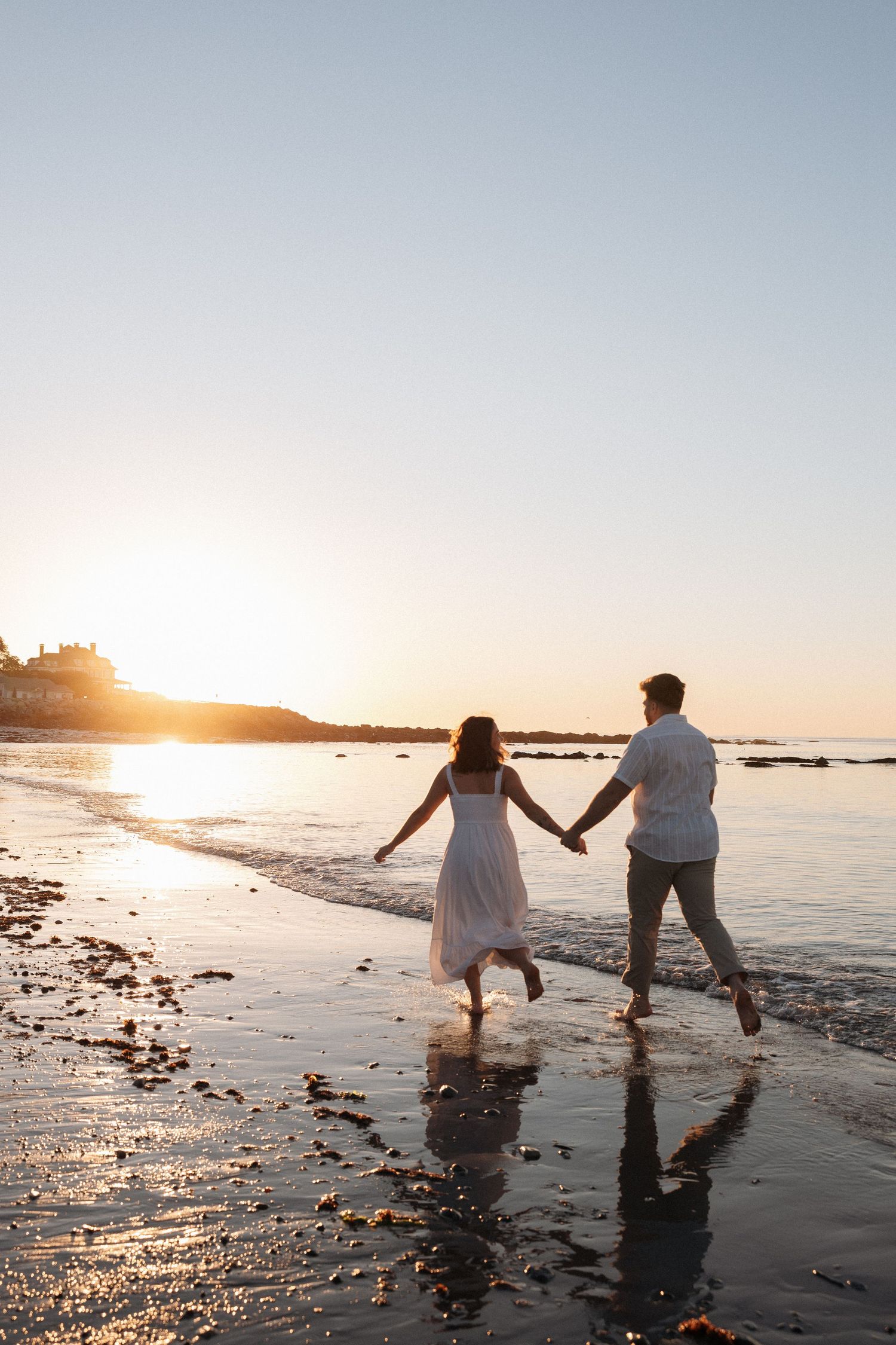 Professional photoshoot at Rye, Beach New Hampshire for sunrise. The golden glow is over the water while they frolic across the shoreline.