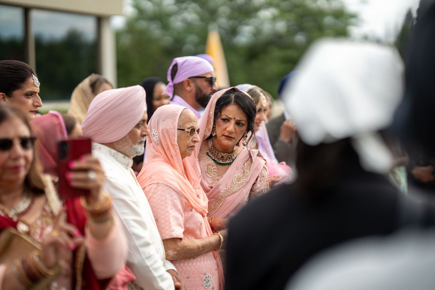 Festive outdoor wedding celebration with guests dancing and celebrating in traditional South Asian attire.