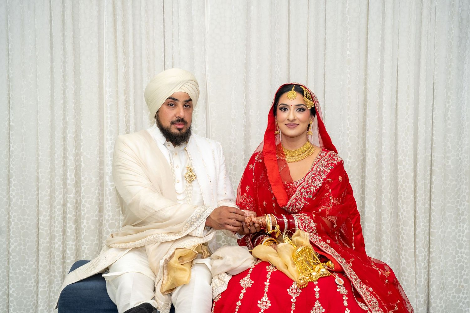 Traditional Sikh wedding ceremony with bride in red and groom in white performing rituals.