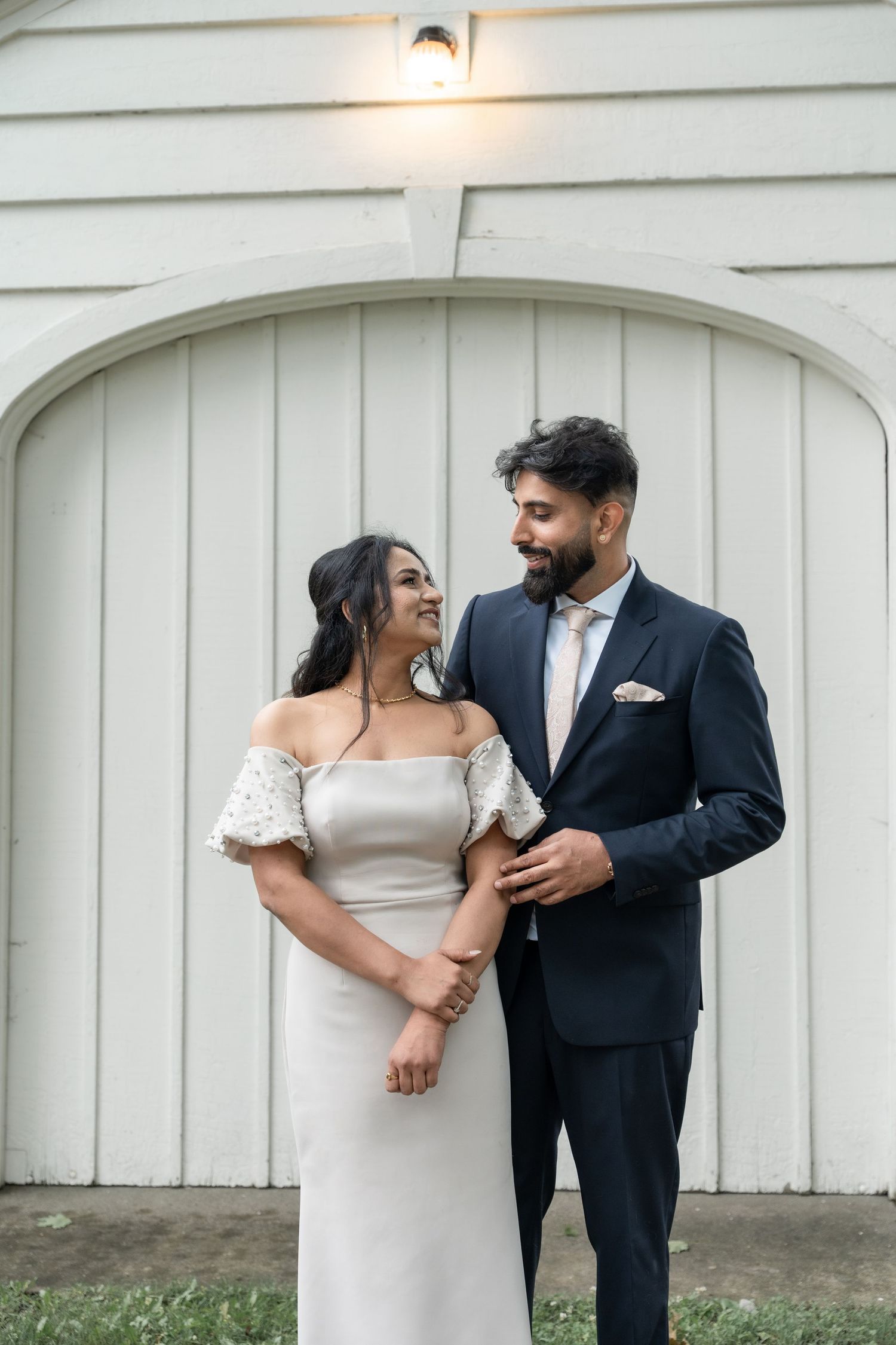 A romantic wedding couple shares intimate moments against a white wooden wall in a series of candid poses.