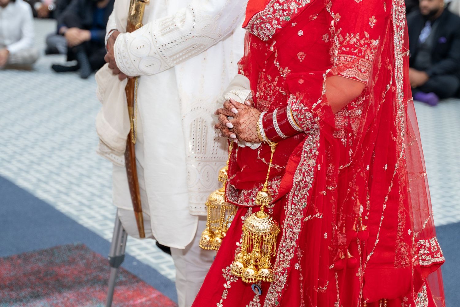 Traditional Indian wedding attire featuring a red and gold embroidered sari with ornate jewelry and accessories.
