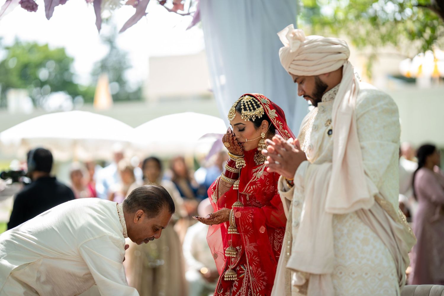 Traditional Indian wedding ceremony with guests in formal attire gathered under outdoor tent.